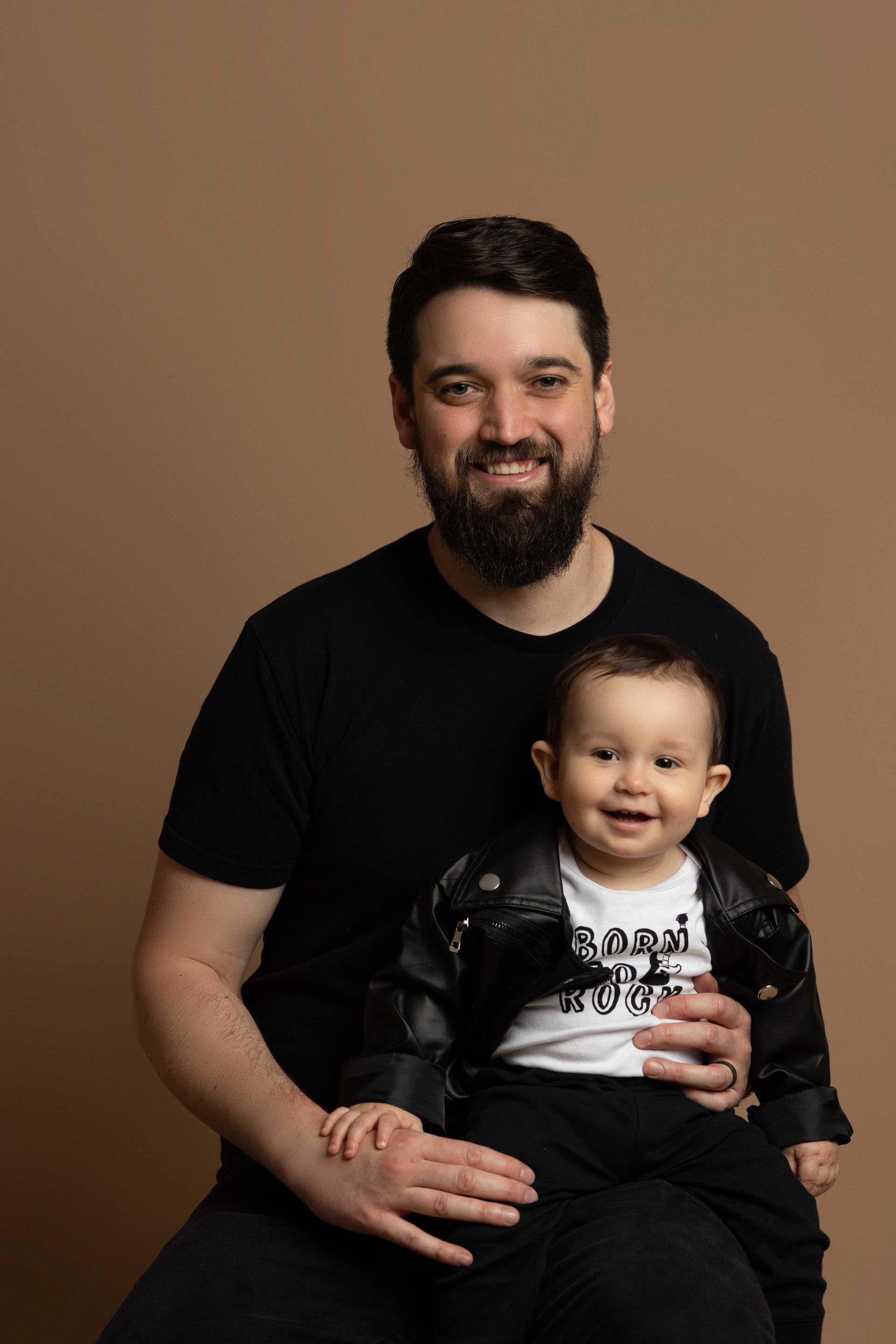 A man with a beard is holding a baby in his arms.