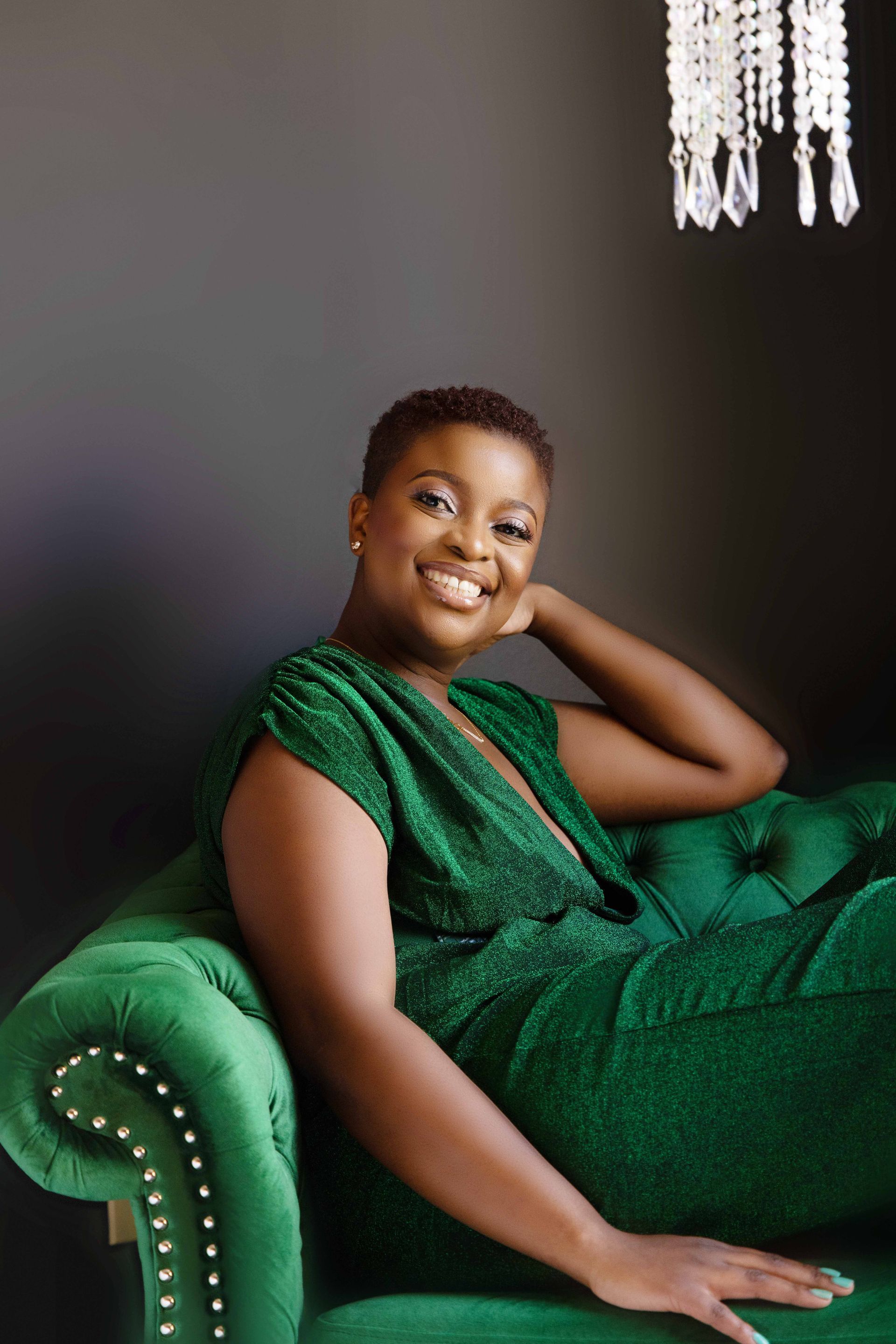 A woman in a green dress is sitting on a green couch.