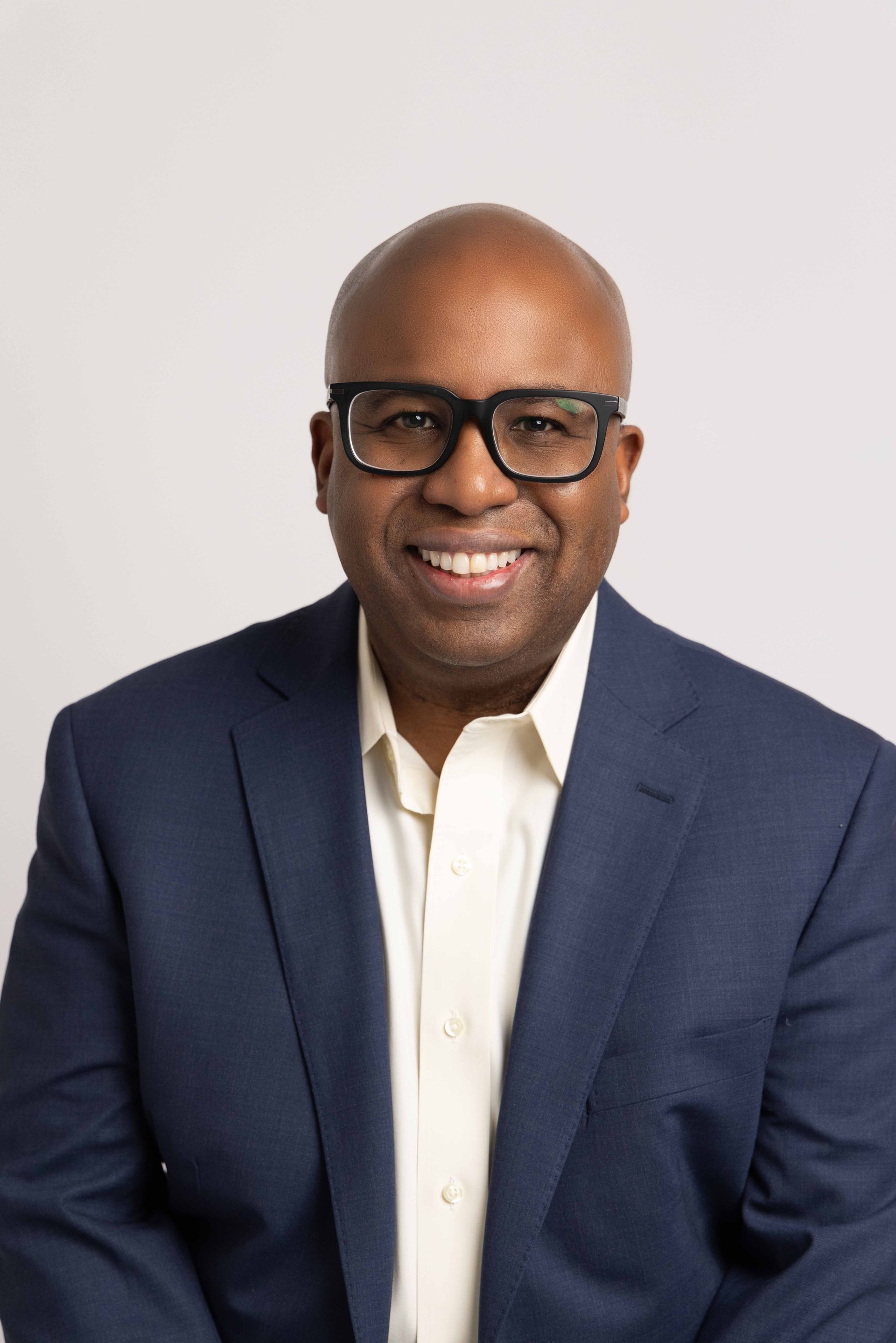 A man in a suit and glasses is smiling for the camera.