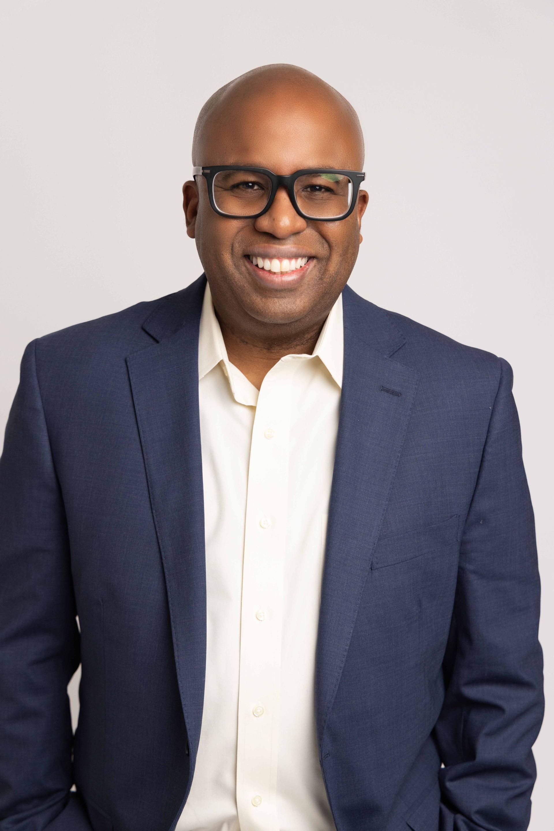 A man in a suit and glasses is smiling for the camera.