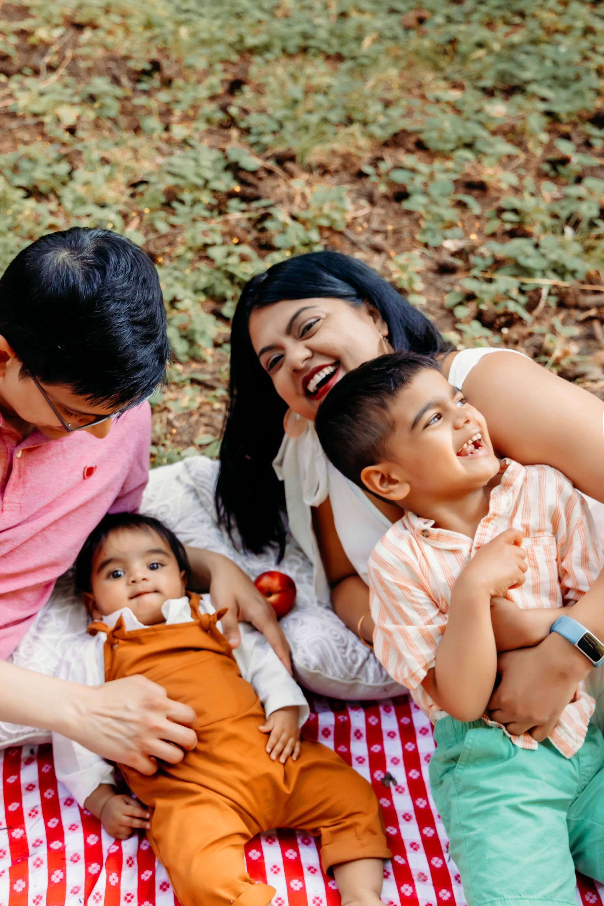 A family is laying on a picnic blanket in the grass.