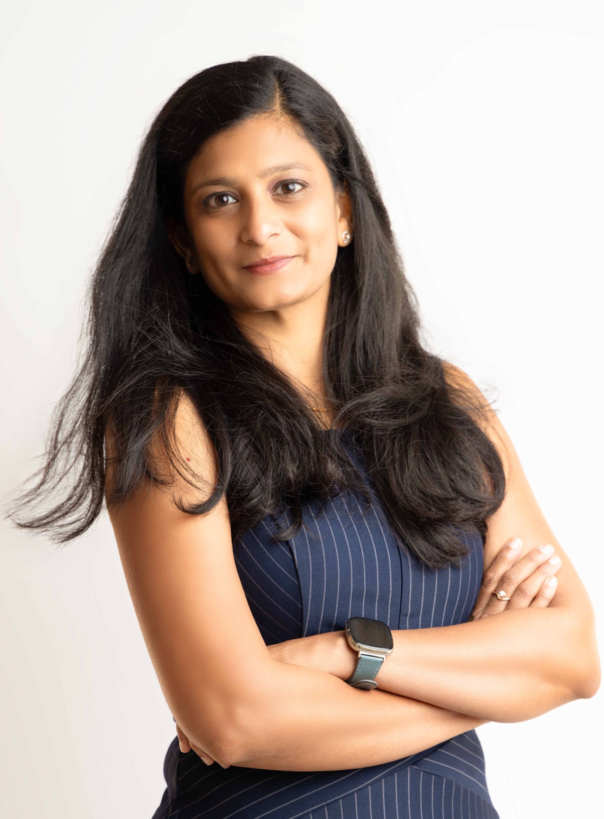 A woman is standing with her arms crossed and wearing a watch.