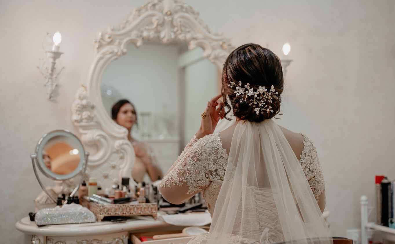 A woman in a wedding dress is looking at herself in a mirror.