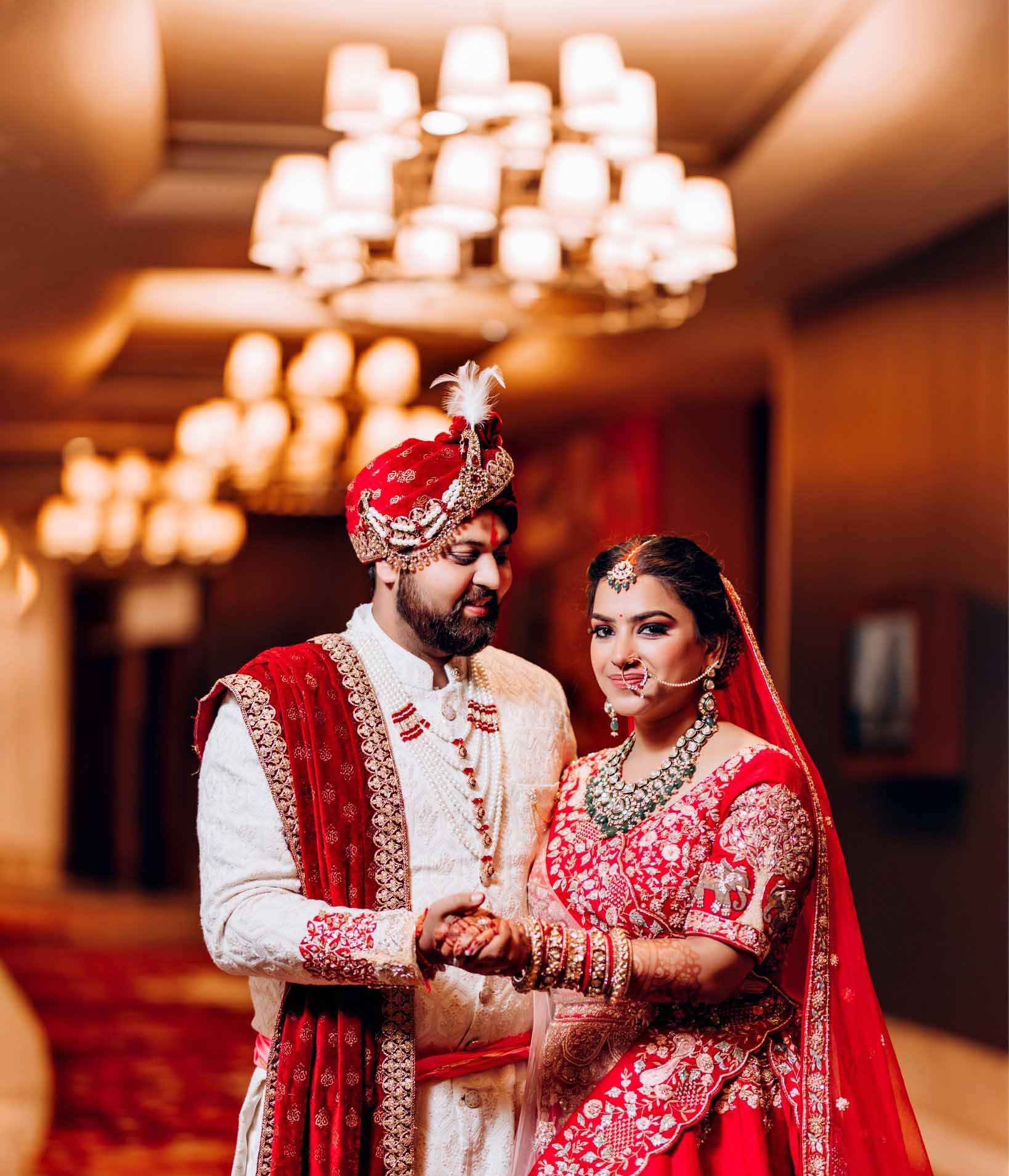 A bride and groom are standing next to each other in a hallway holding hands.