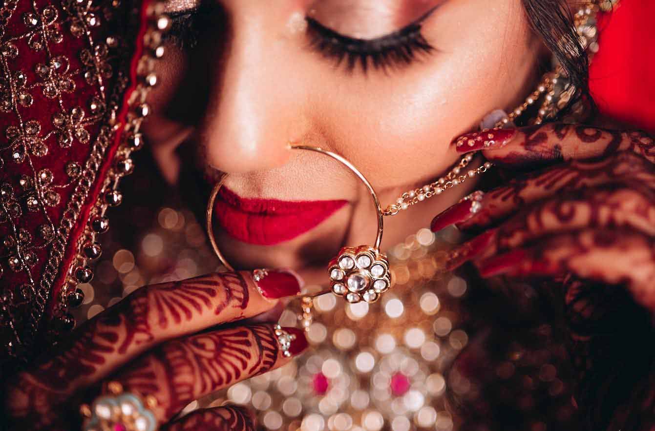 A close up of a woman wearing a nose ring and a necklace.