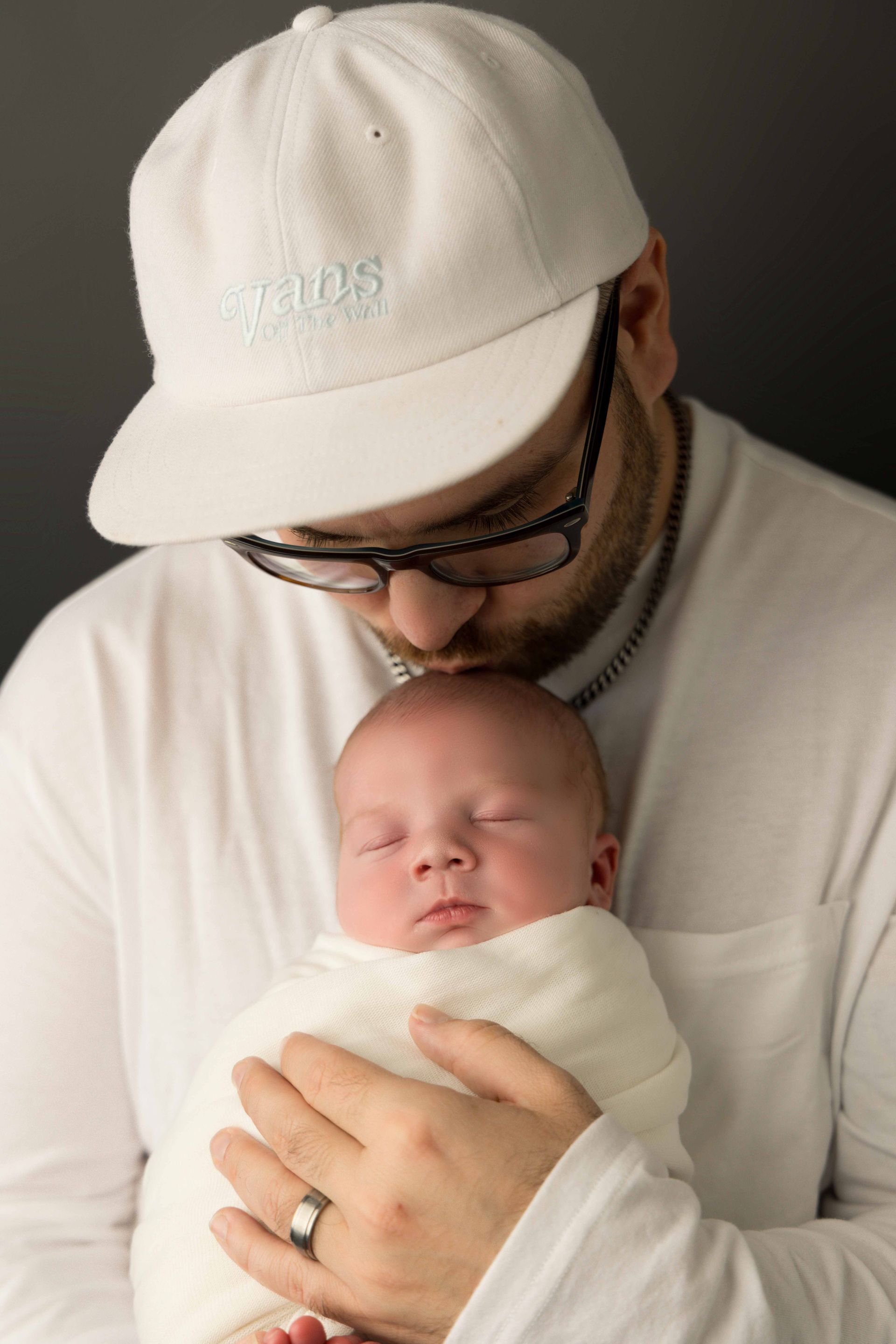 A man is holding a newborn baby wrapped in a blanket.