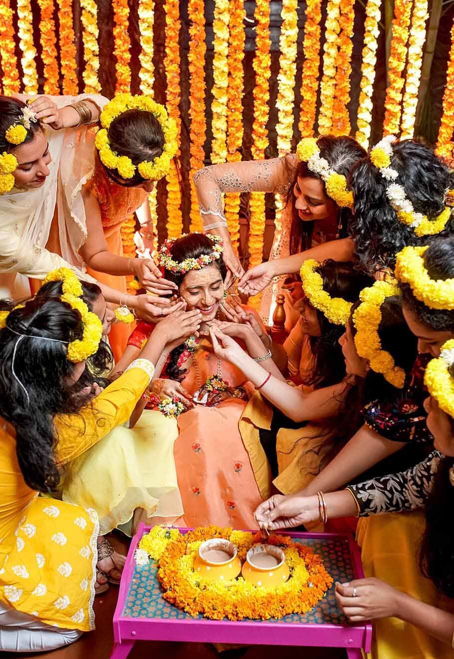 A group of women are sitting around a table with flowers in their hair.