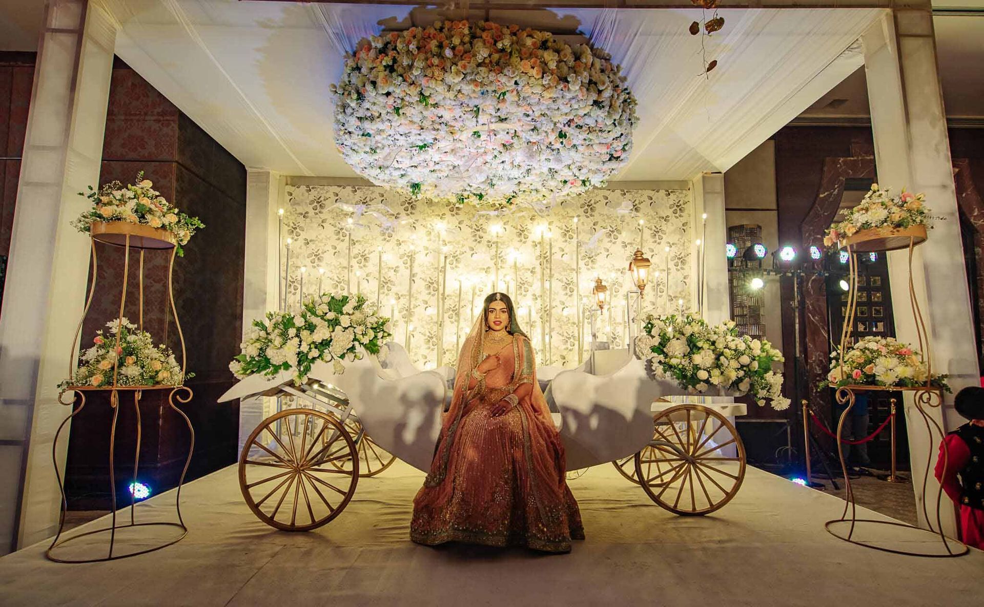 A bride in a wedding dress is sitting on a horse drawn carriage.