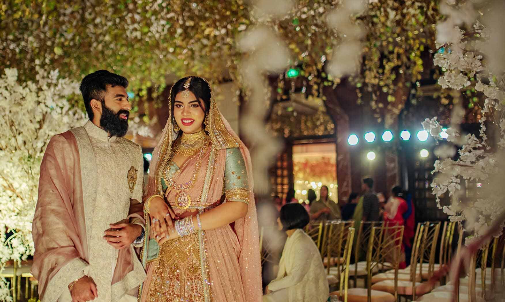 A bride and groom are posing for a picture at their wedding reception.
