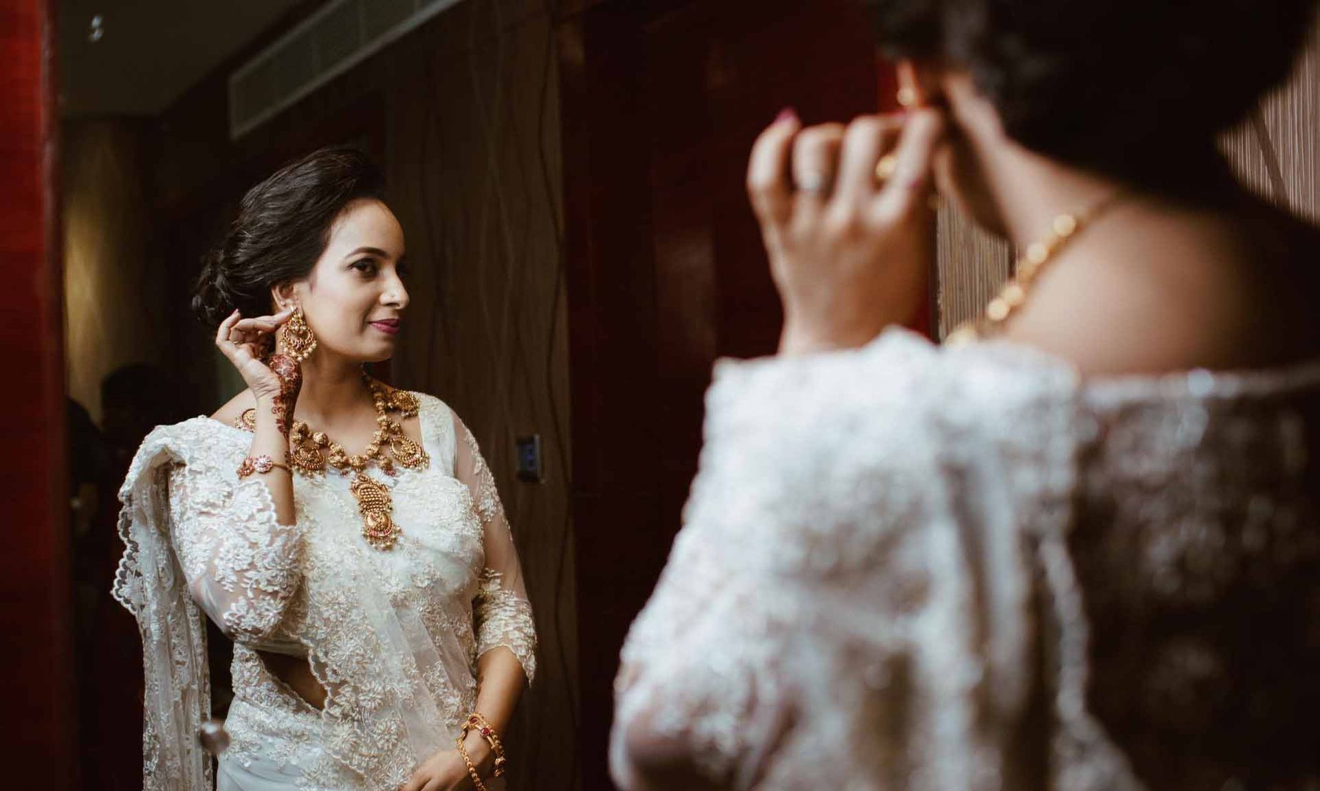 A woman in a white dress is looking at herself in the mirror.