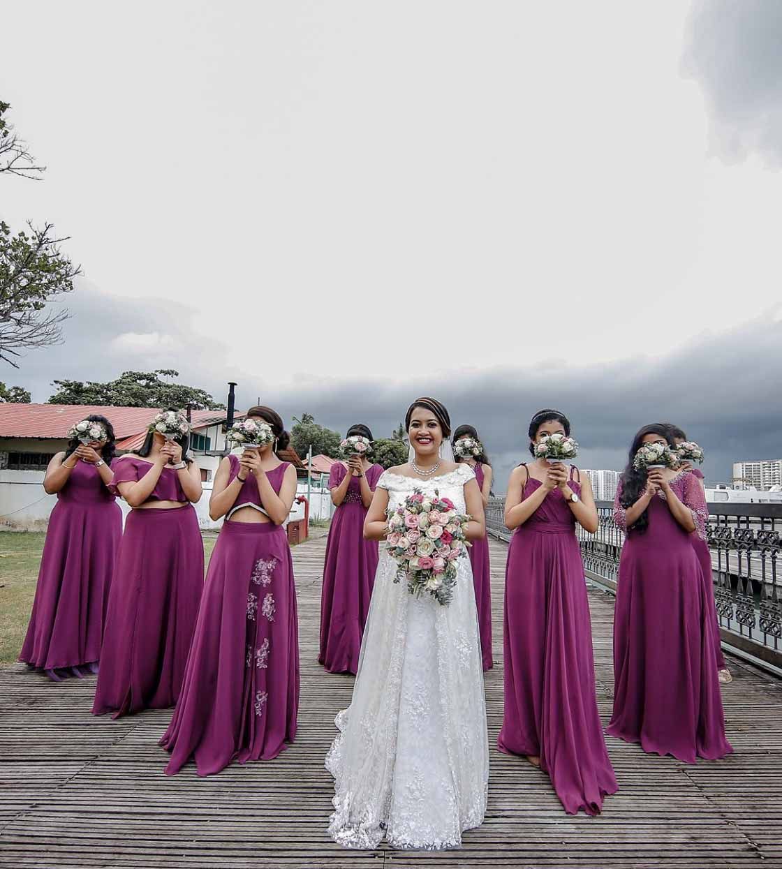 A bride and her bridesmaids are standing on a wooden deck.