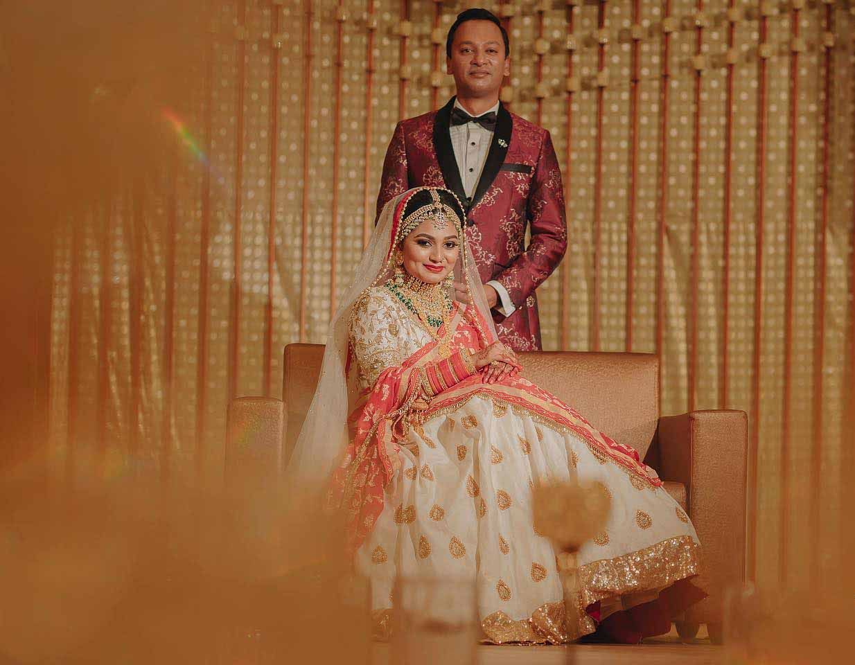 A bride and groom are posing for a picture at their wedding reception.