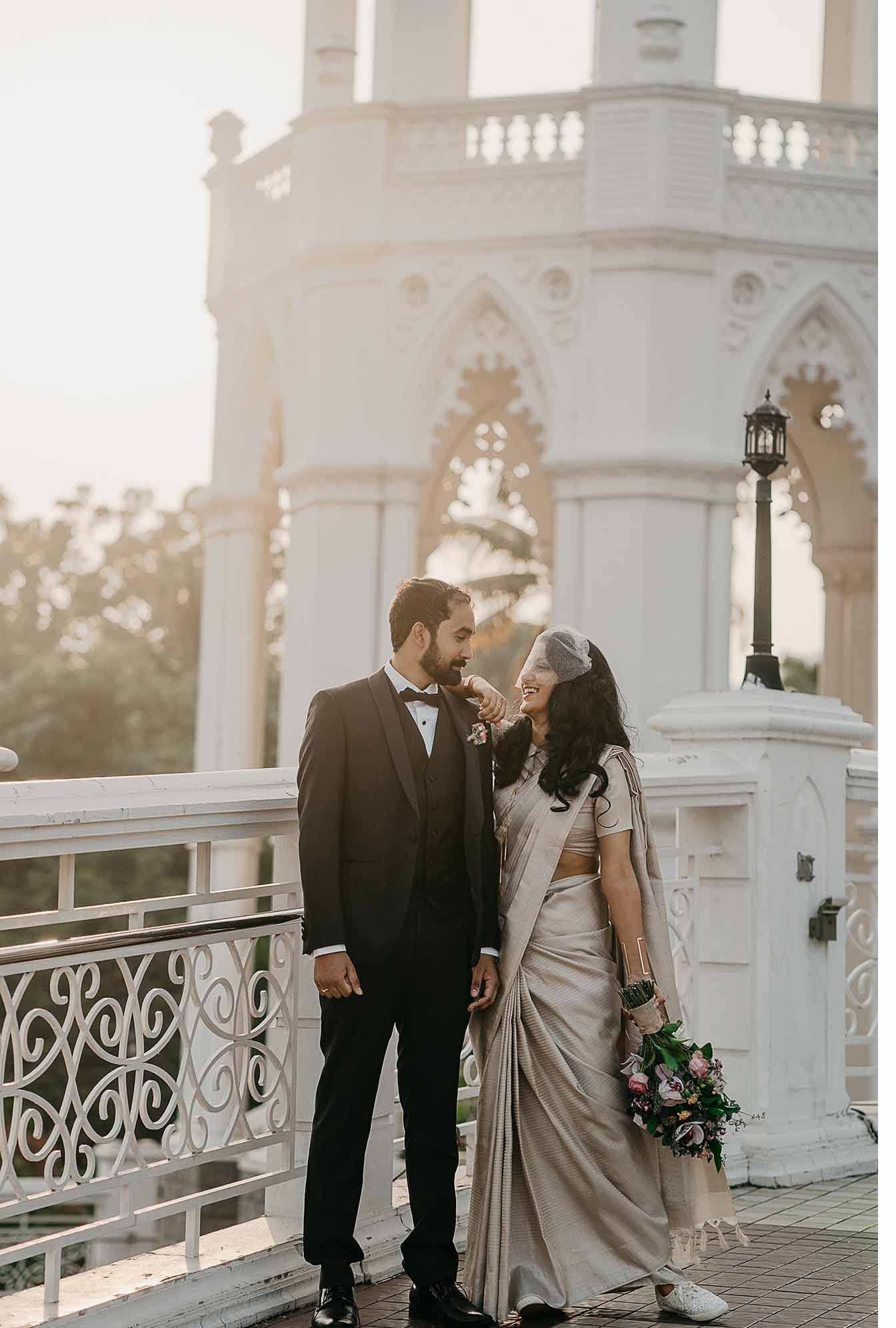A bride and groom are posing for a picture on a bridge.