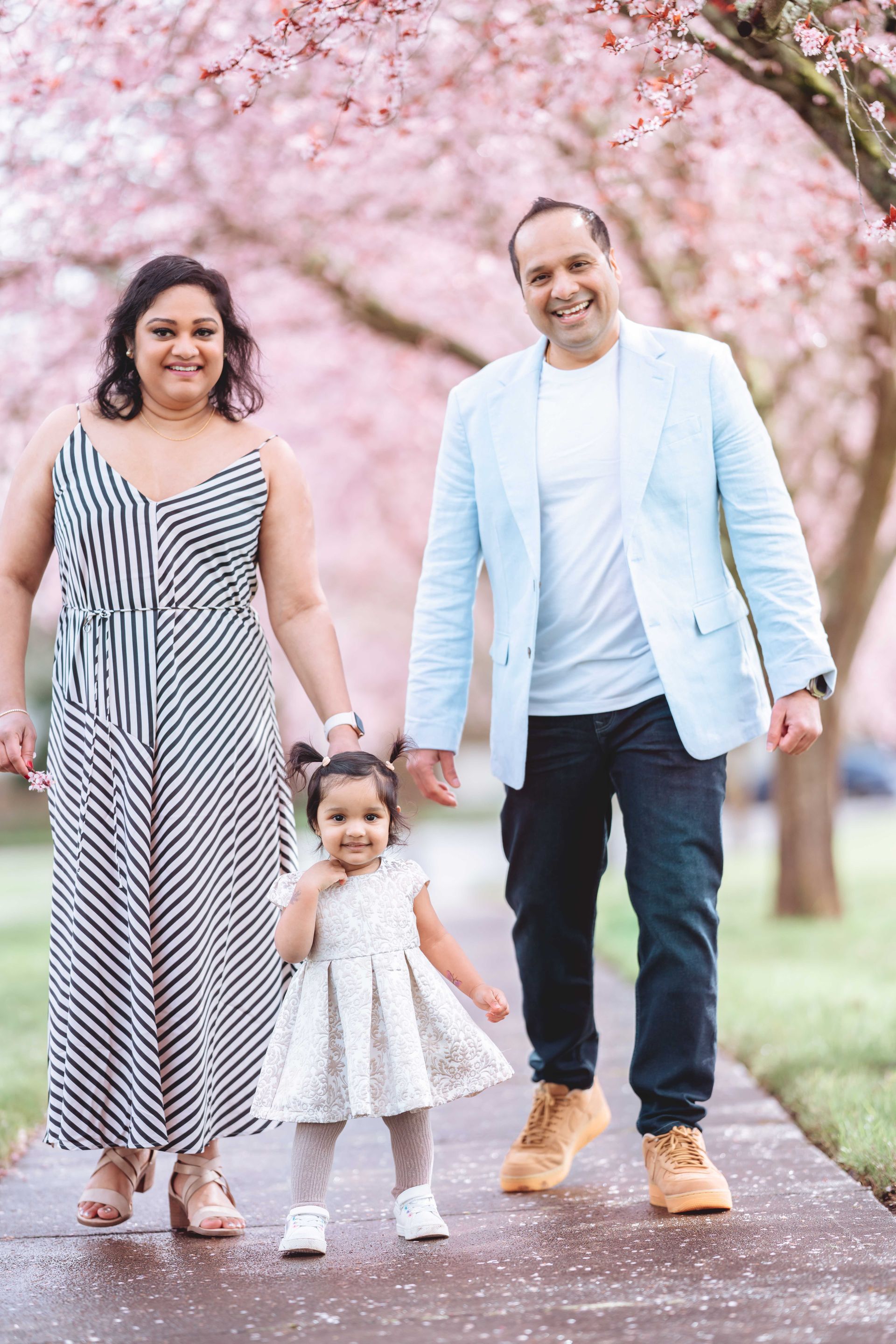 A woman in a wedding dress and hijab is sitting in front of a floral wall.