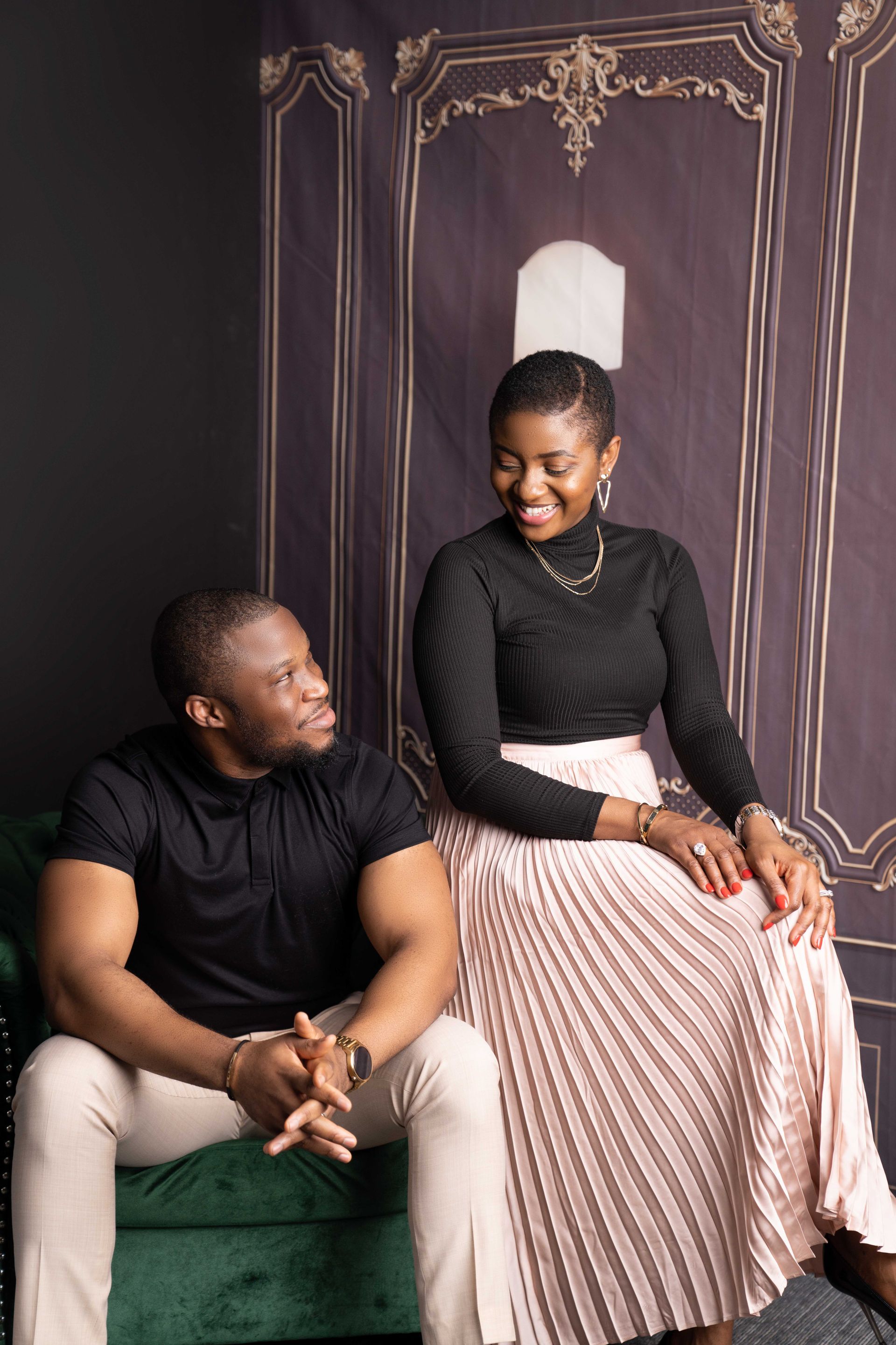 A man and a woman are sitting on a green couch.