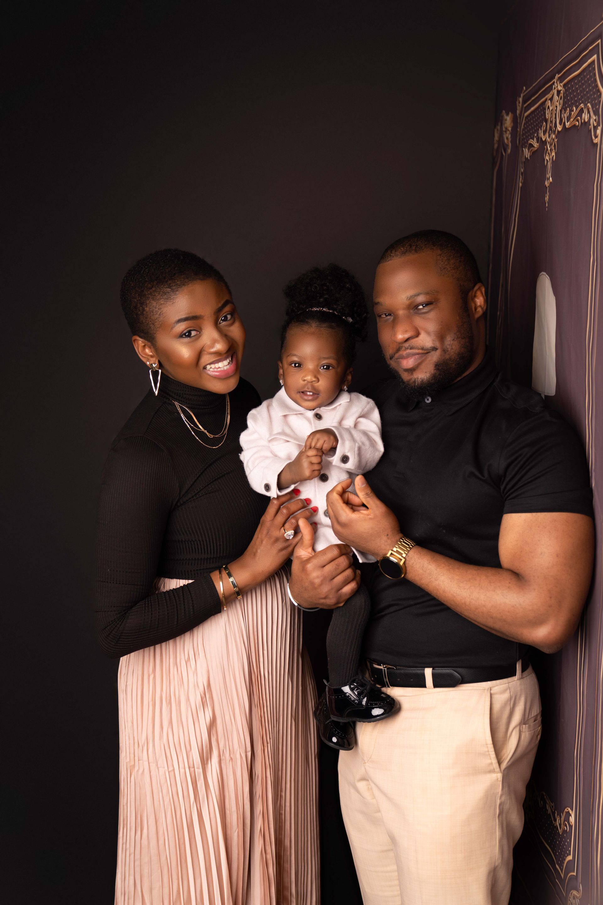 A man and woman are standing next to each other holding a baby.