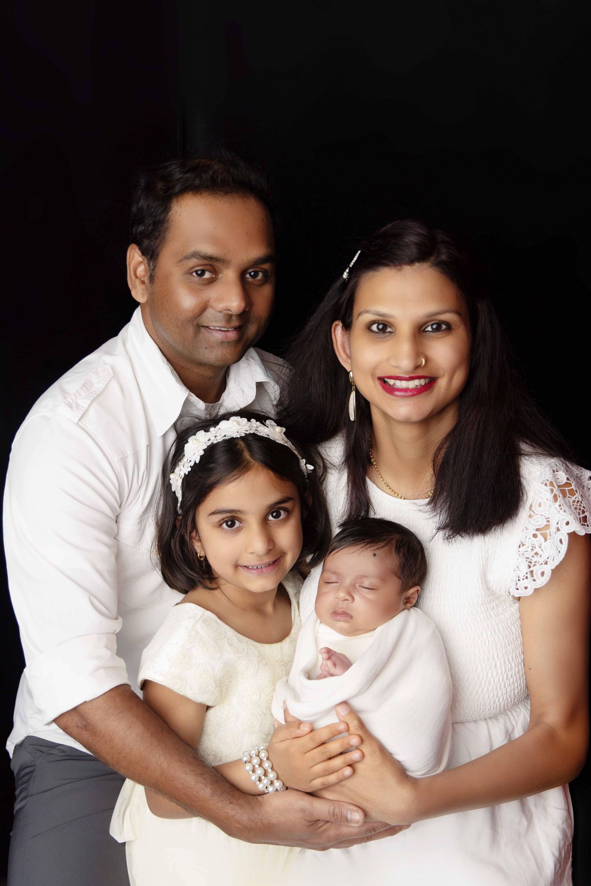 A family is posing for a picture with a newborn baby.