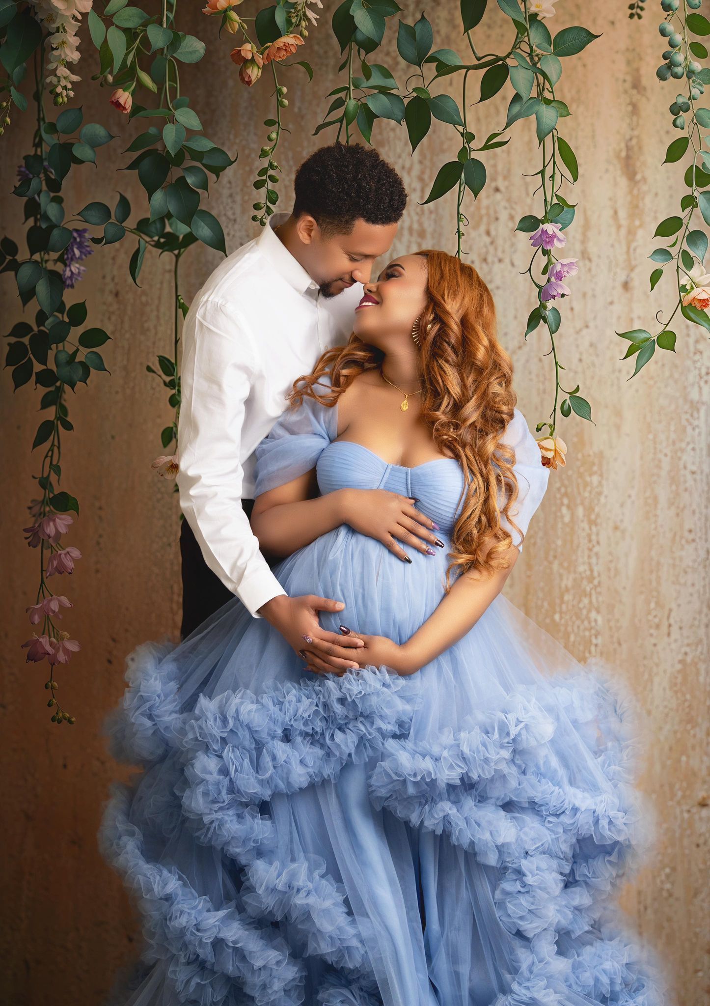 A pregnant woman in a blue dress is standing next to a man in a white shirt.