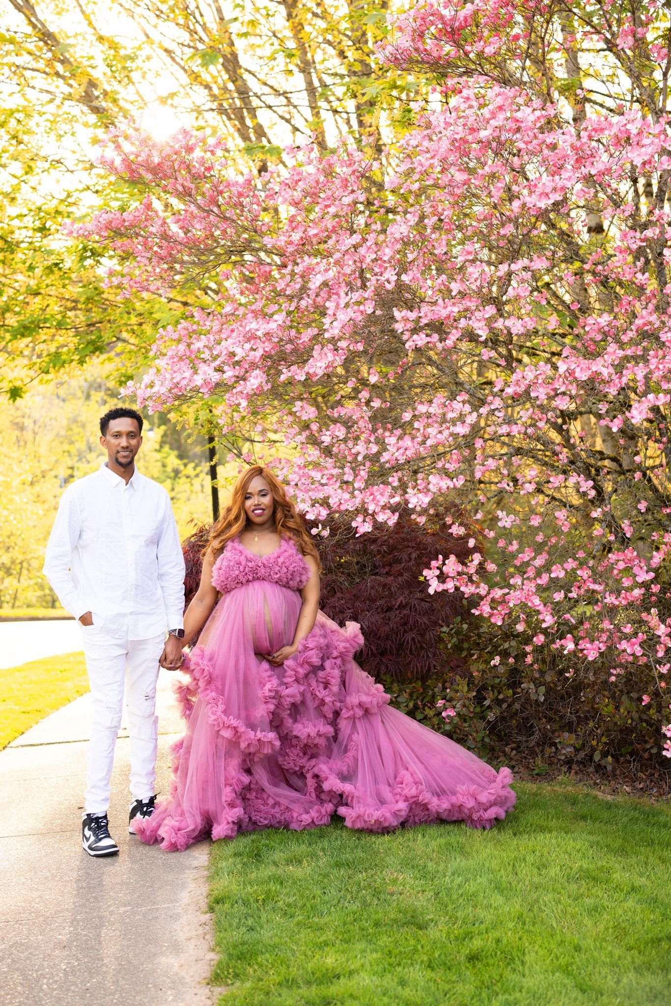 A pregnant woman in a purple dress is standing next to a man in a white shirt.