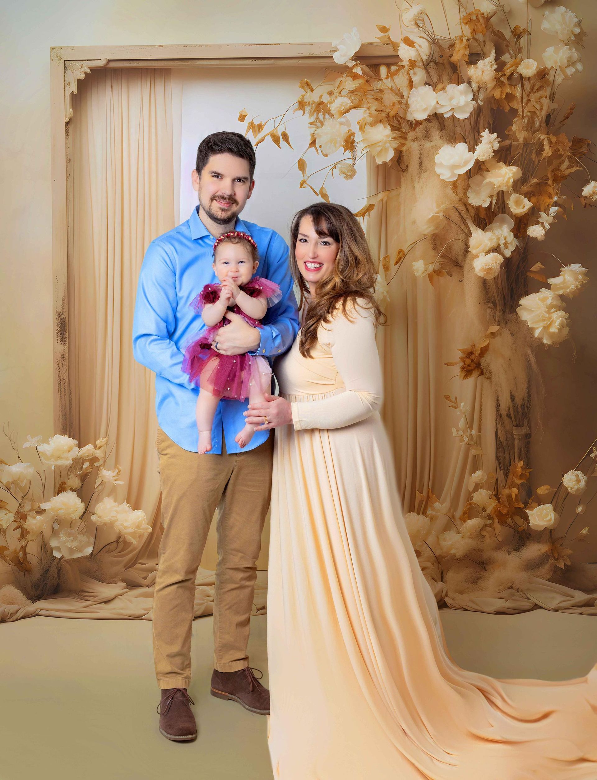 A pregnant woman is posing for a picture with her husband and baby.