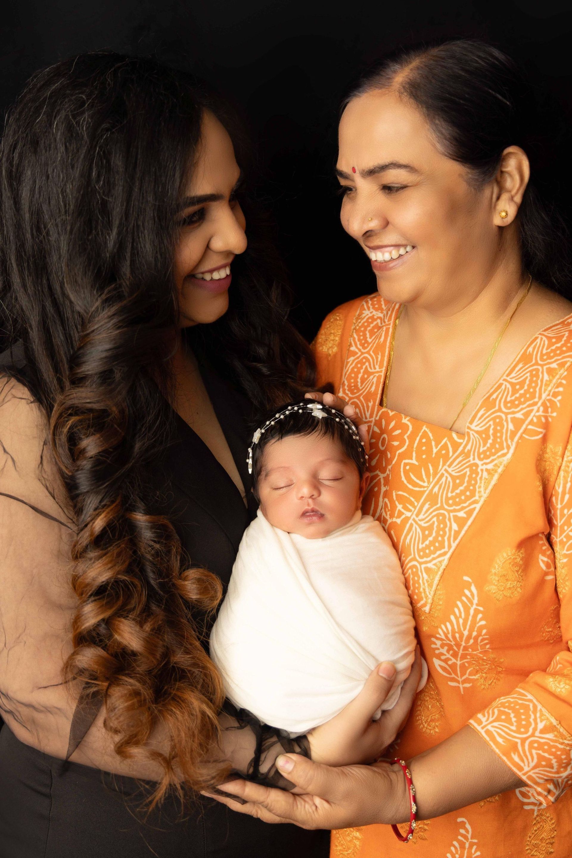 Two women are holding a newborn baby in their arms.