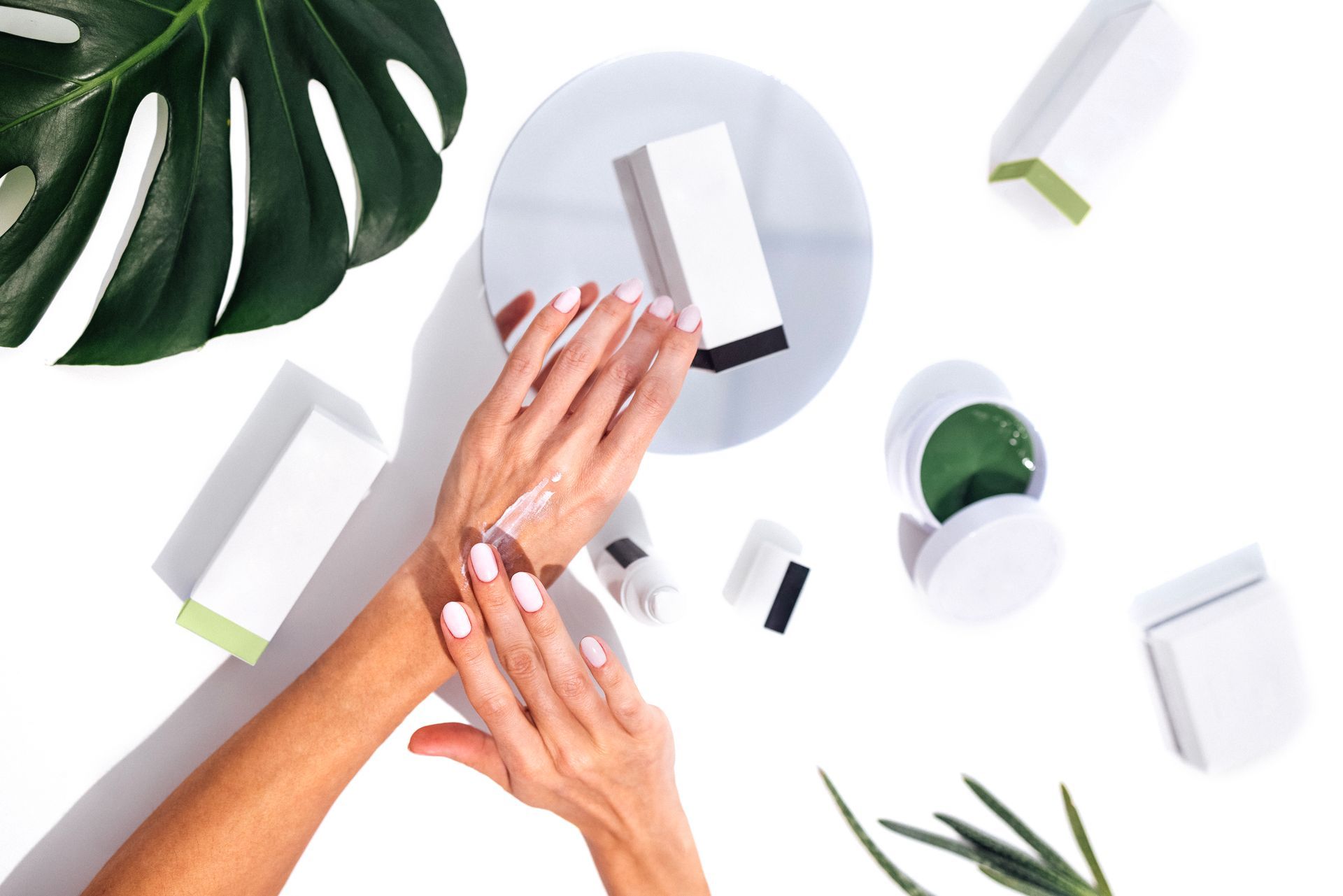 A woman is applying lotion to her hands on a table.