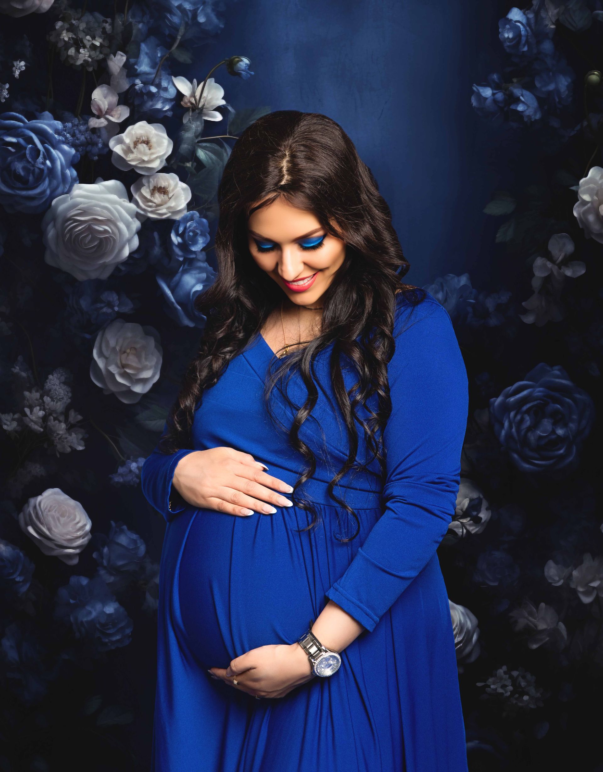 A pregnant woman in a blue dress is holding her belly.