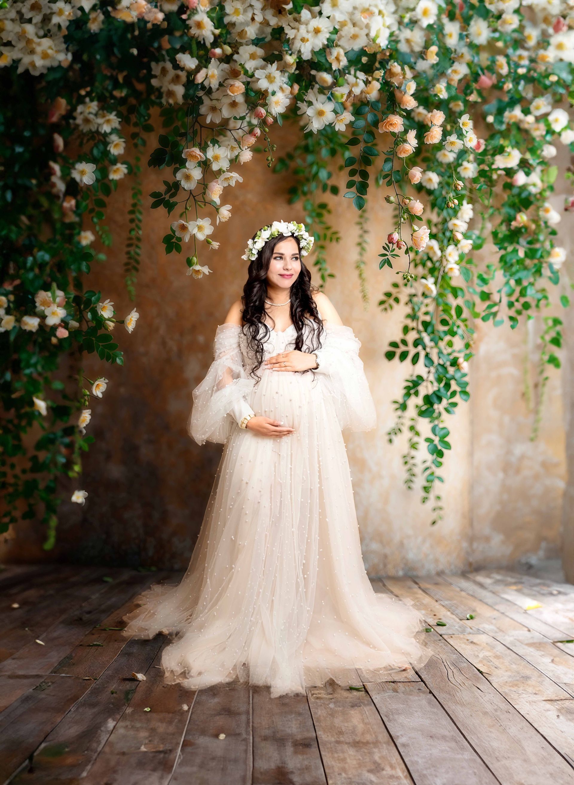 A pregnant woman is wearing a white dress and a flower crown.