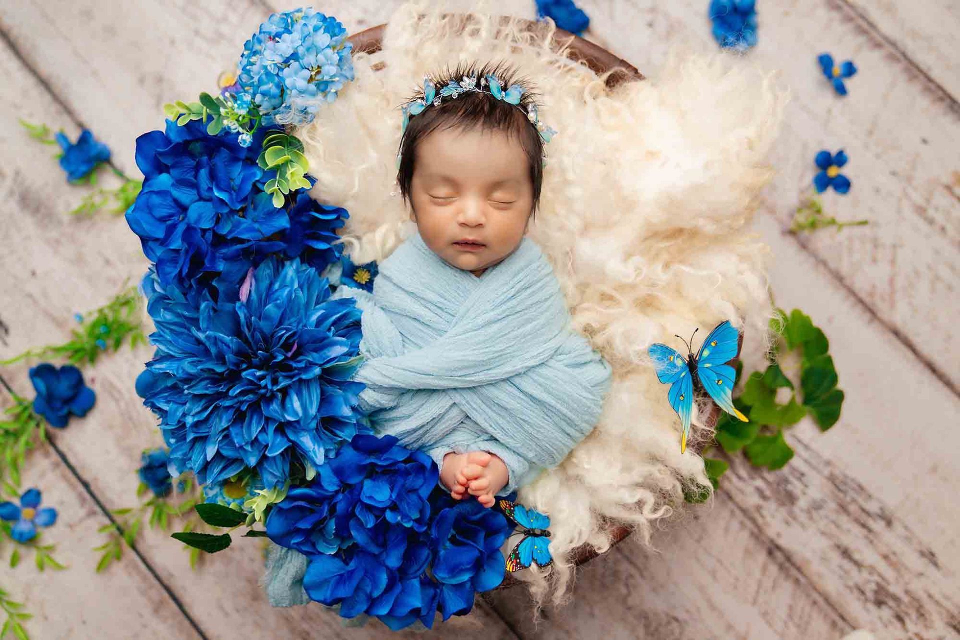 Sleeping baby with beautiful arrangement of blue flowers