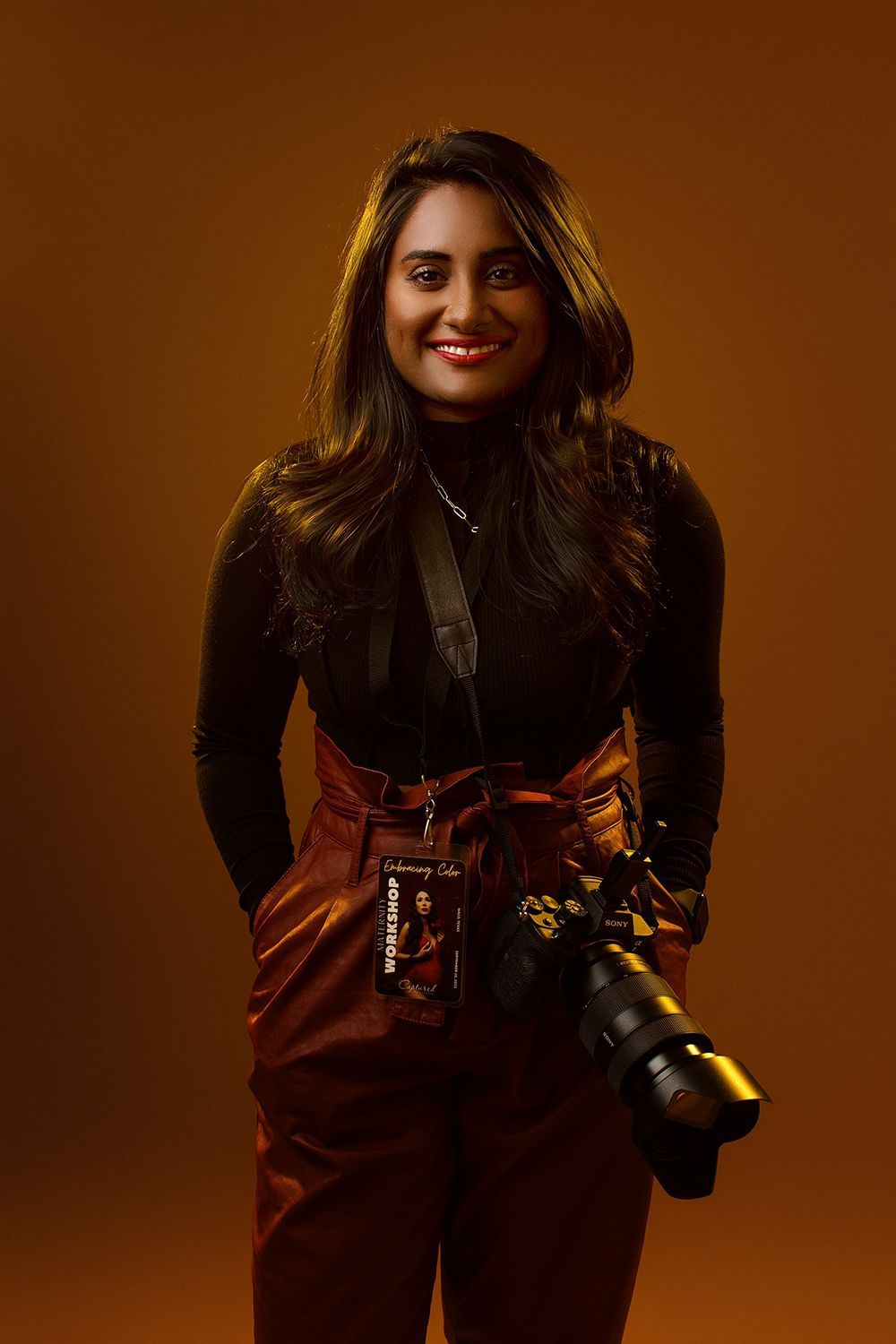 A woman is standing with a camera strapped on her shoulder