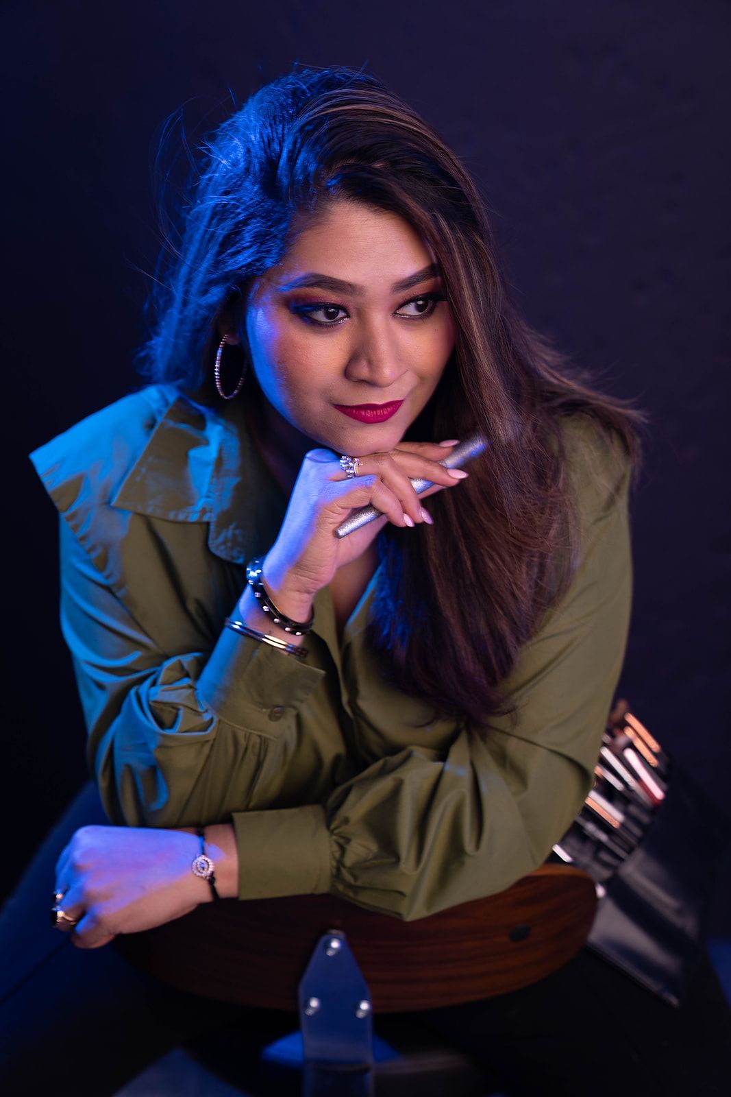 A woman in a green shirt is sitting at a table with her hand on her chin