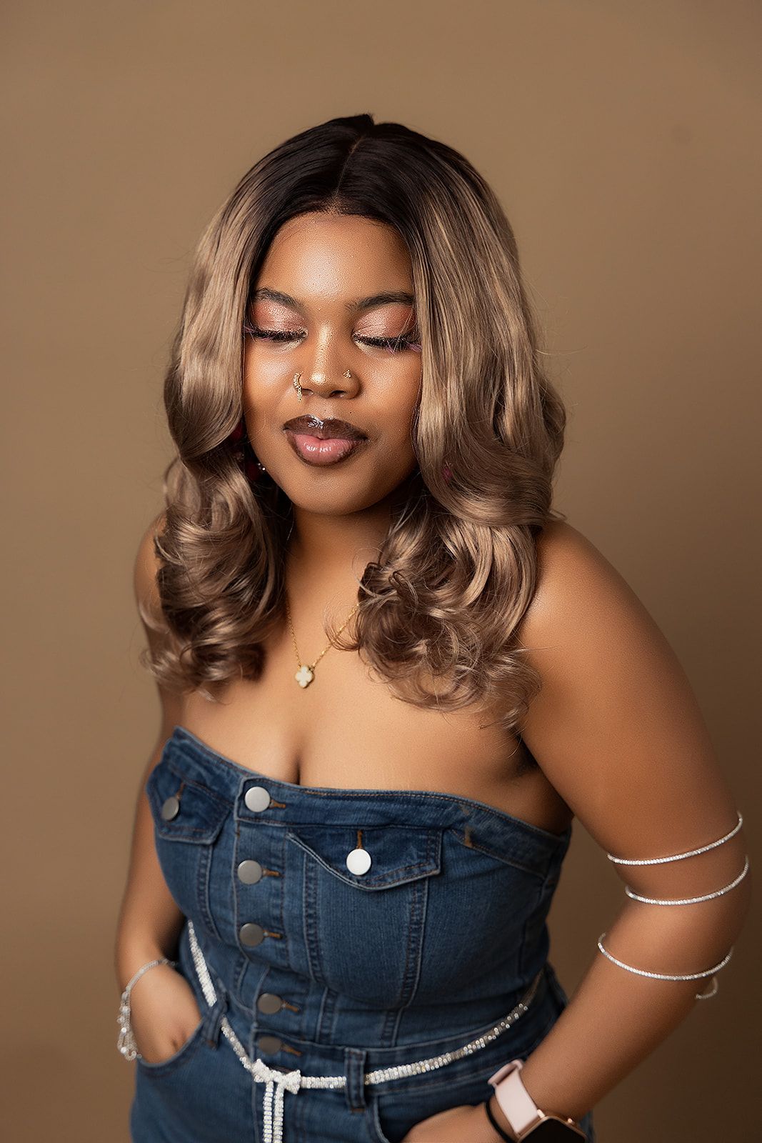 A woman in a denim dress is standing with her hands in her pockets.