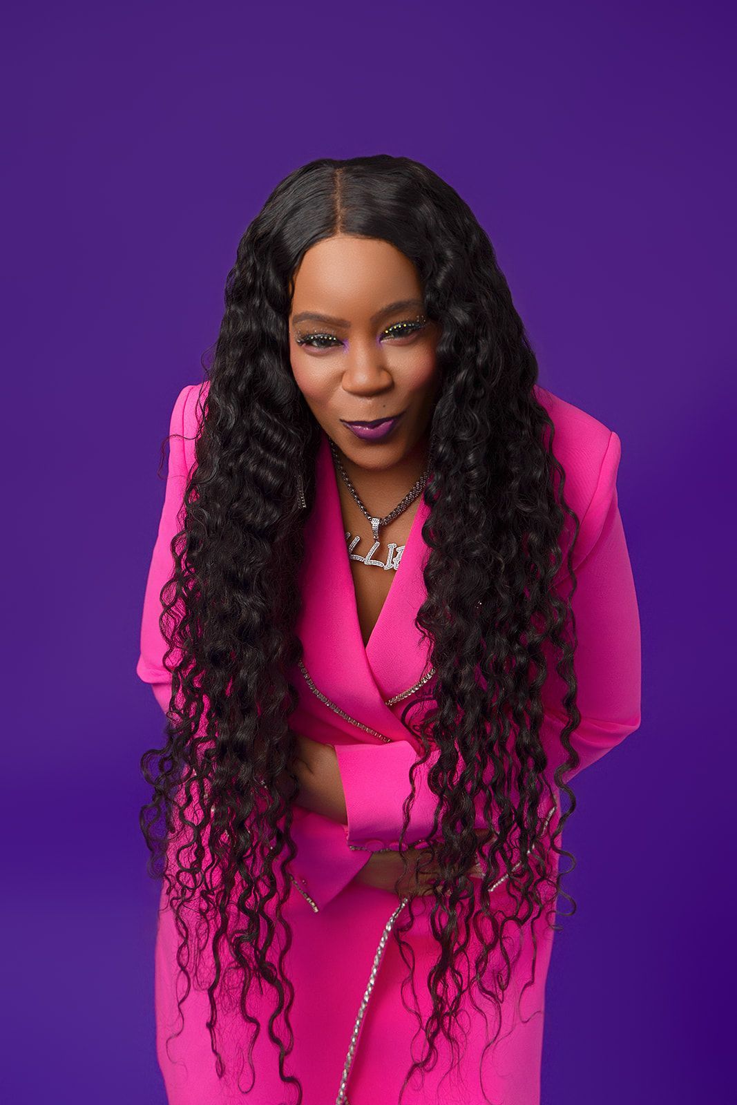 A woman in a pink suit with long curly hair