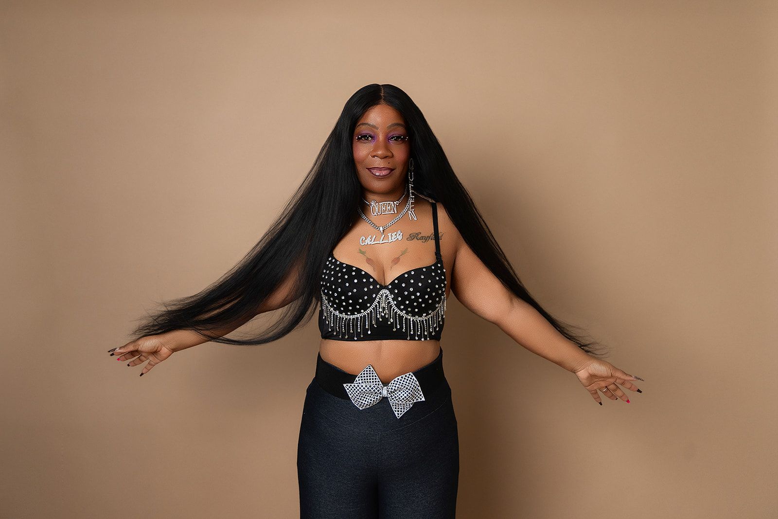 A woman with very long hair is standing with her arms outstretched.