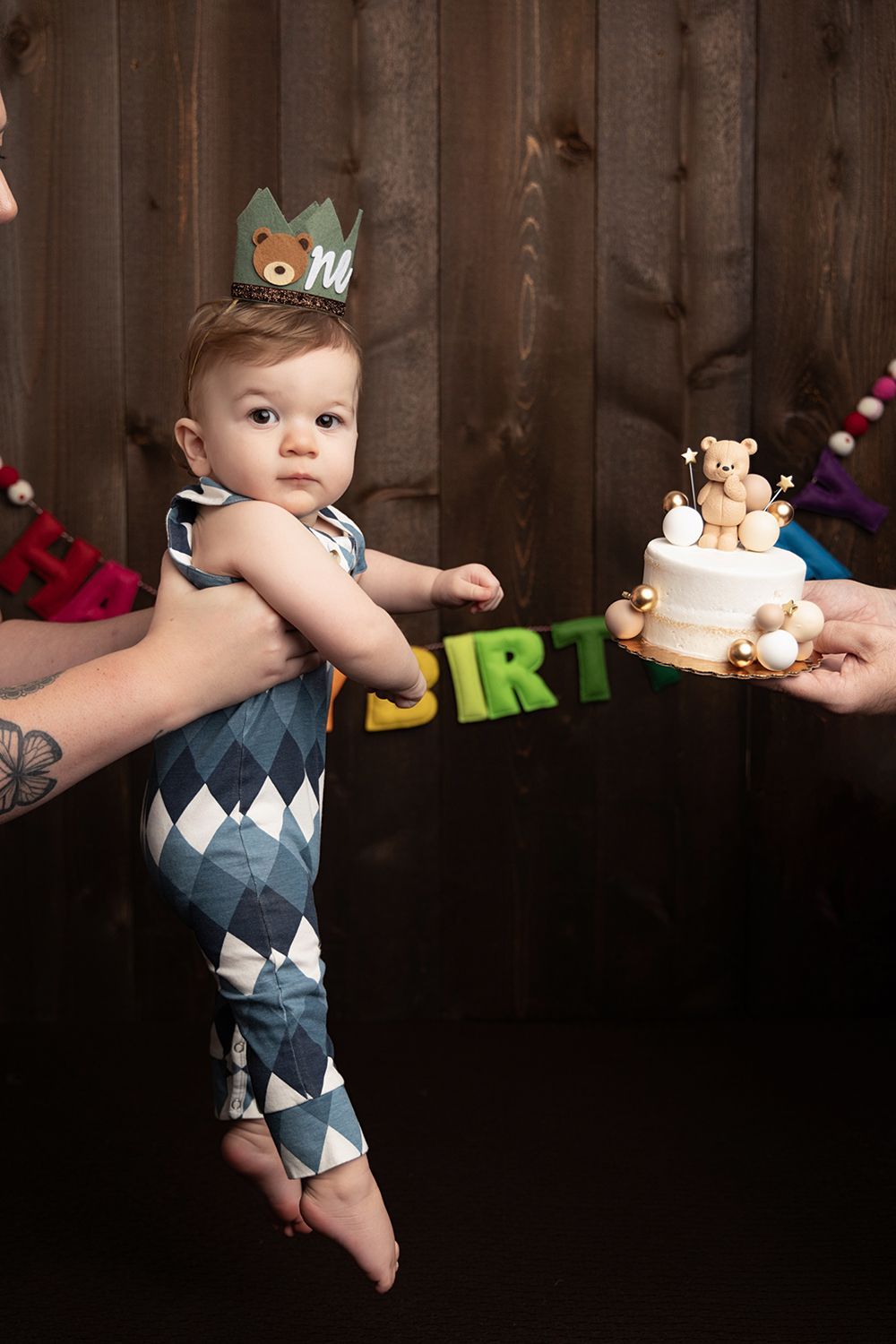 A baby is wearing a crown and a birthday cake
