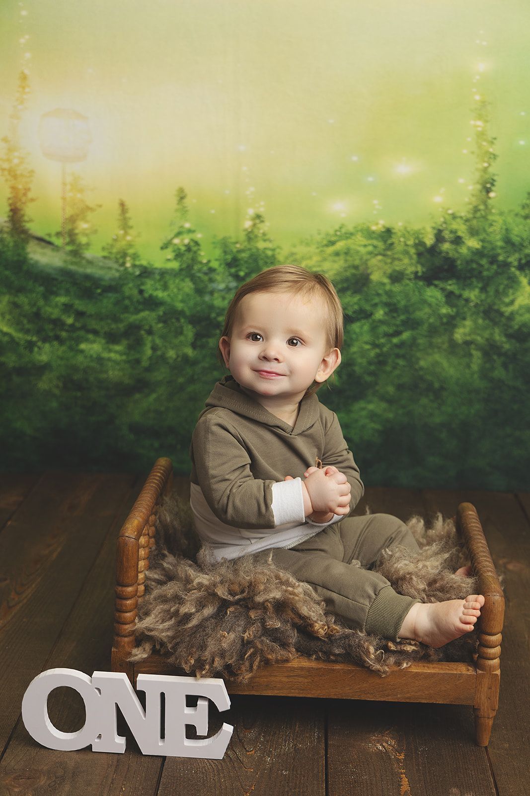 A baby is sitting on a wooden bed next to a sign that says