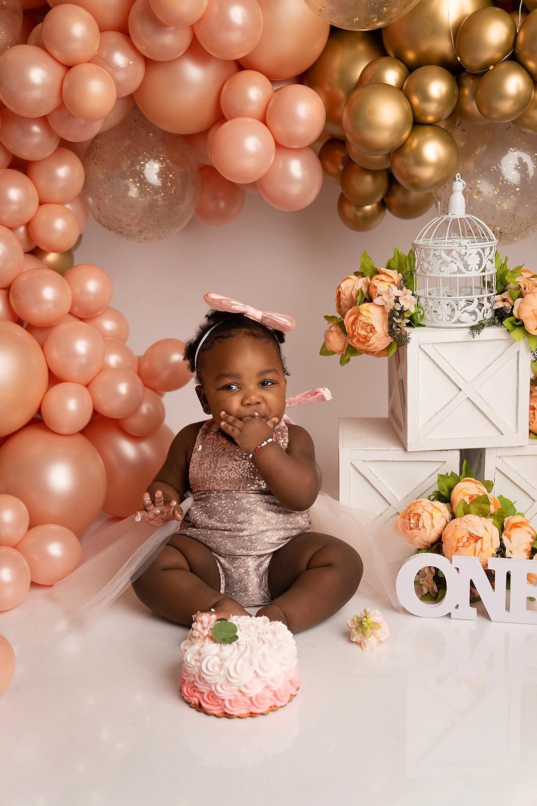 A baby girl is sitting on the floor eating a cake