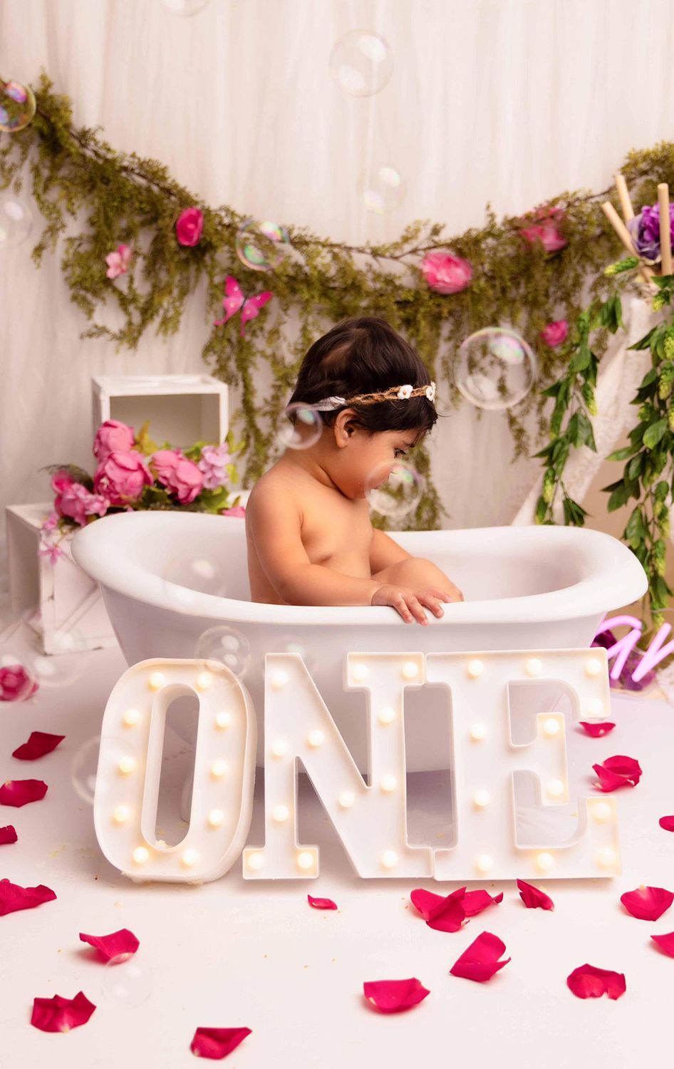 A baby is taking a bath in a bathtub with a sign that says