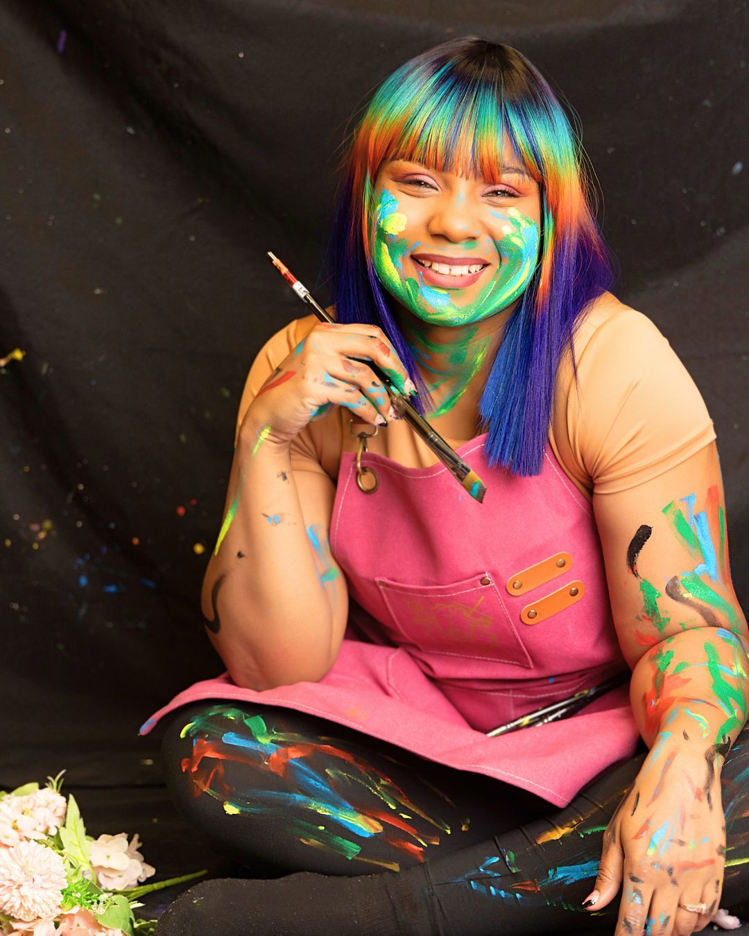 A woman with paint on her face is holding a brush