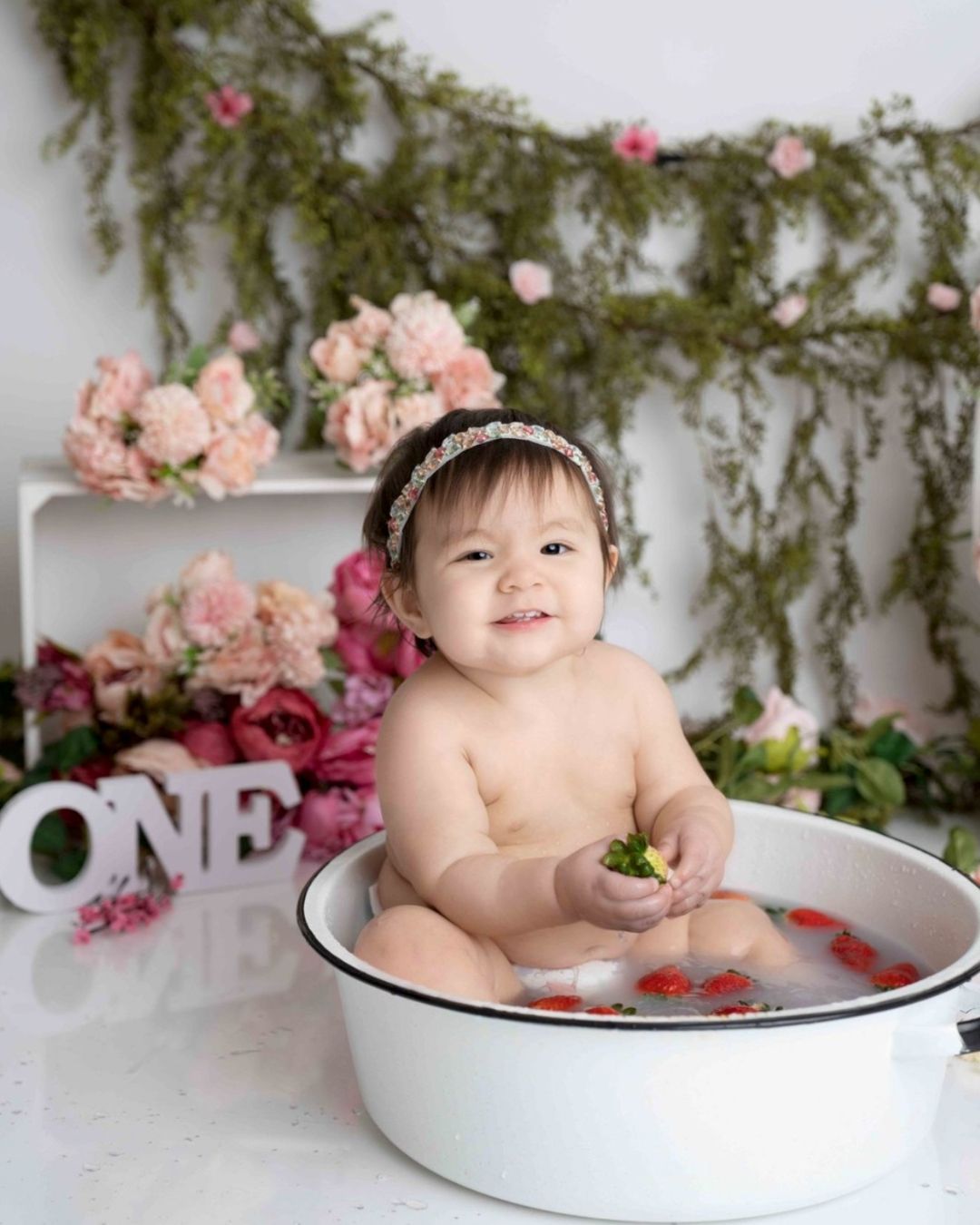 A baby is sitting in a bowl with flowers