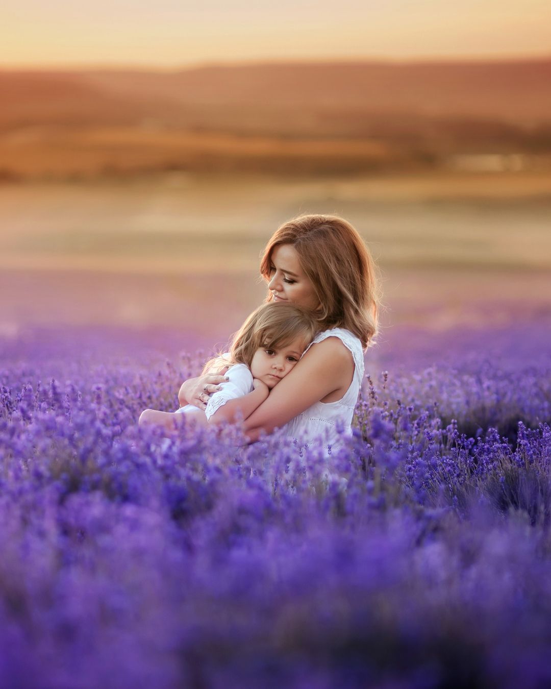 A woman is holding a little girl in a lavender field