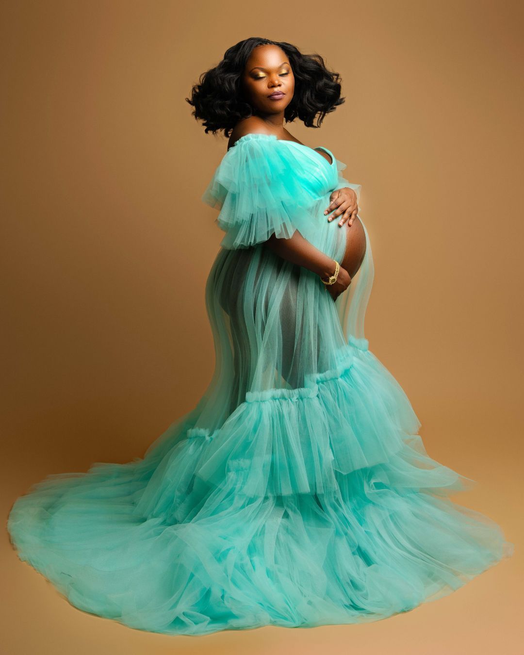 A pregnant woman is wearing a long green tulle dress