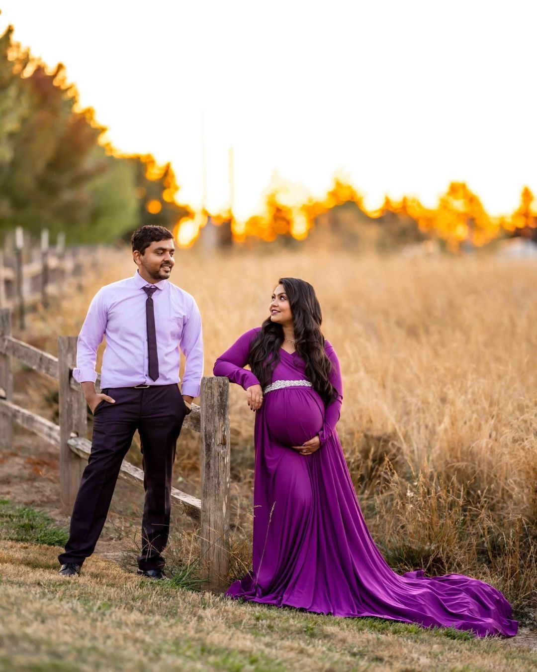 A man and a pregnant woman are standing next to each other in a field