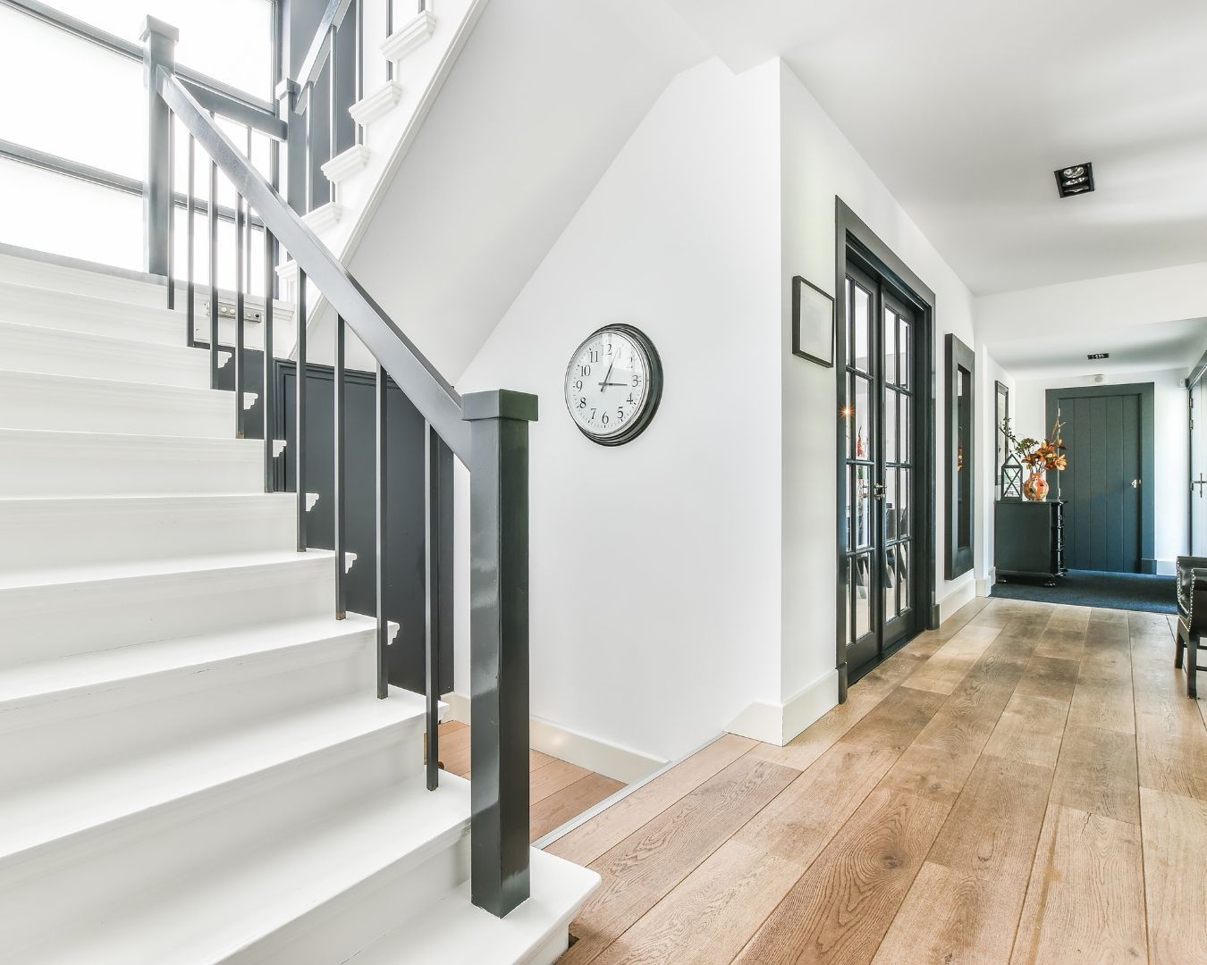 A hallway with stairs and a clock on the wall