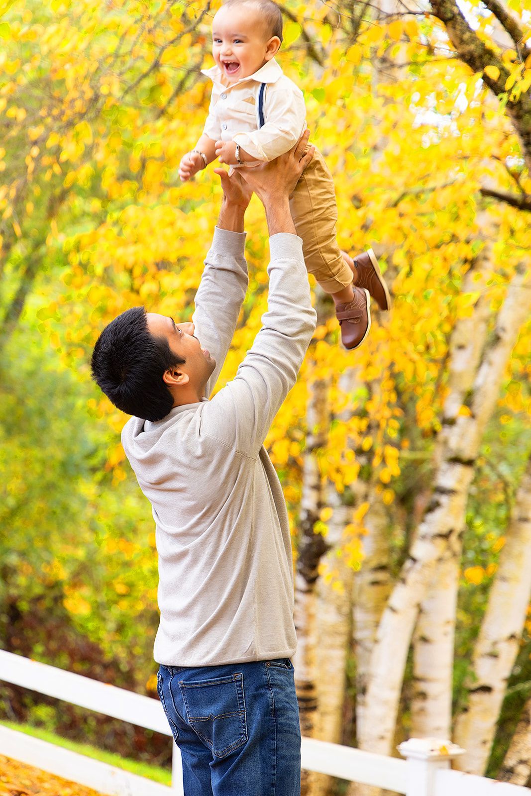 A man is holding a baby up in the air.