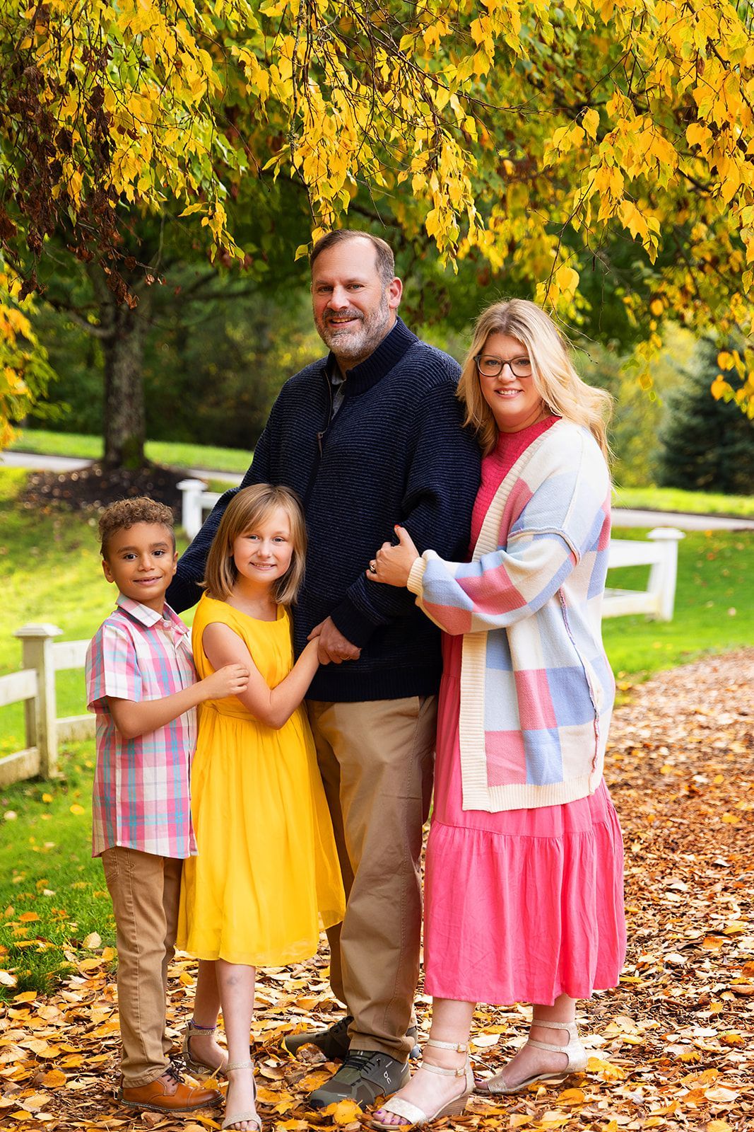 A family is posing for a picture in front of a tree