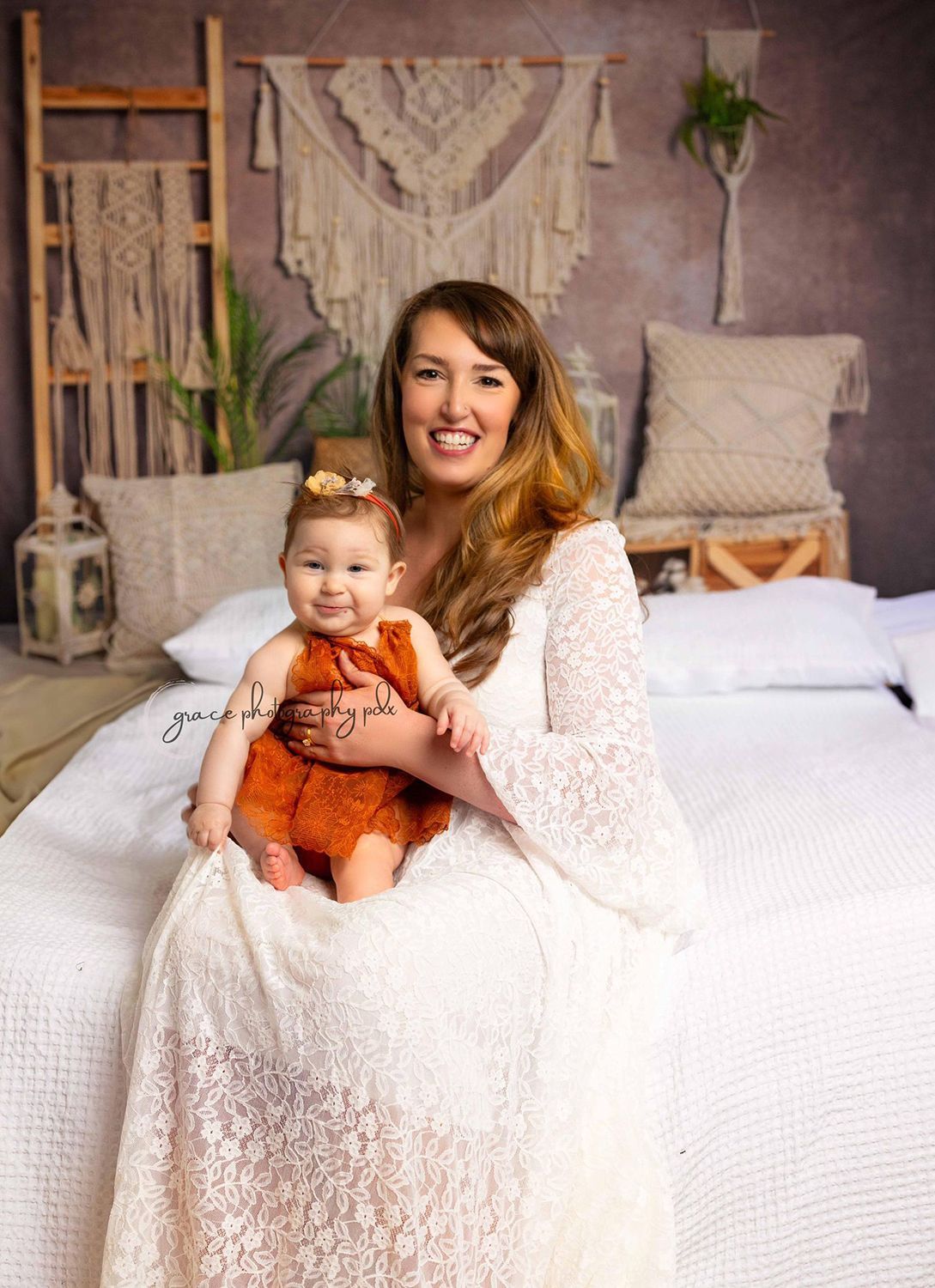 A woman is sitting on a bed holding a baby