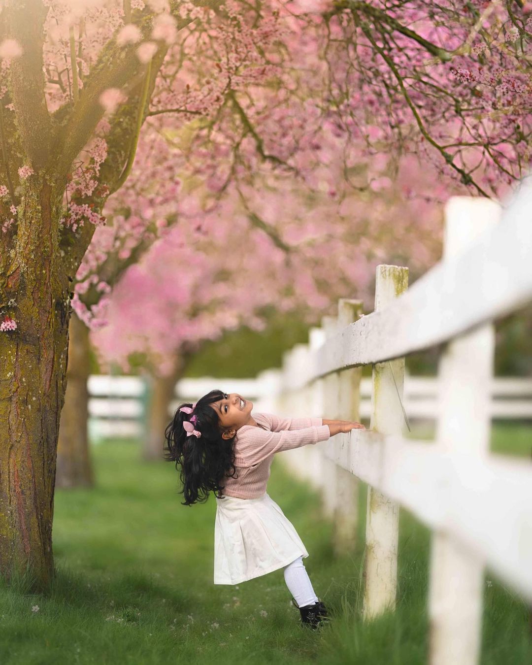 A little girl is playing with the fence