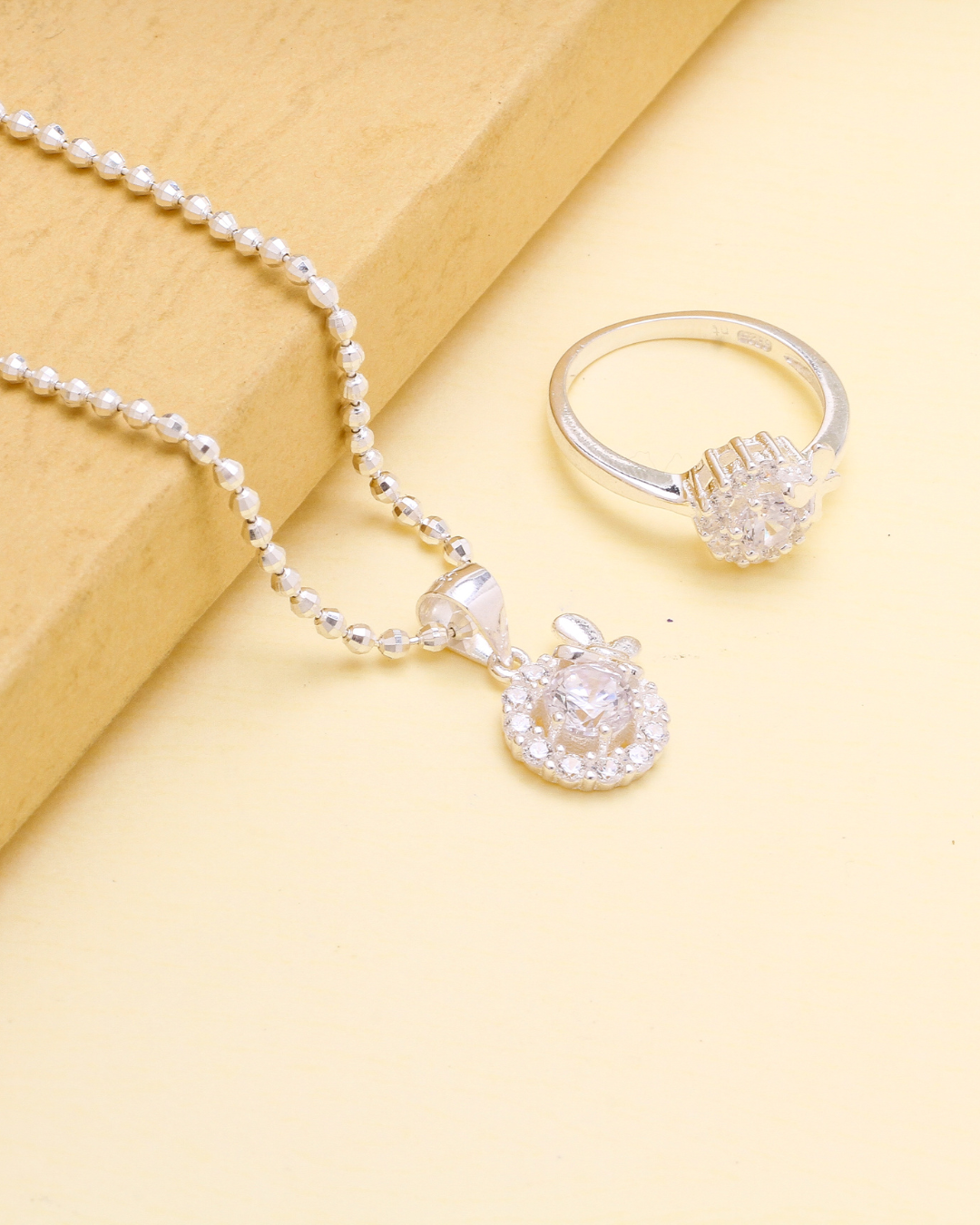 A necklace and a ring are sitting on a table.