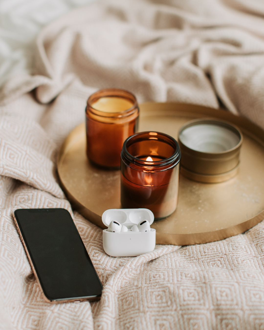 A tray of candles and a cell phone on a bed